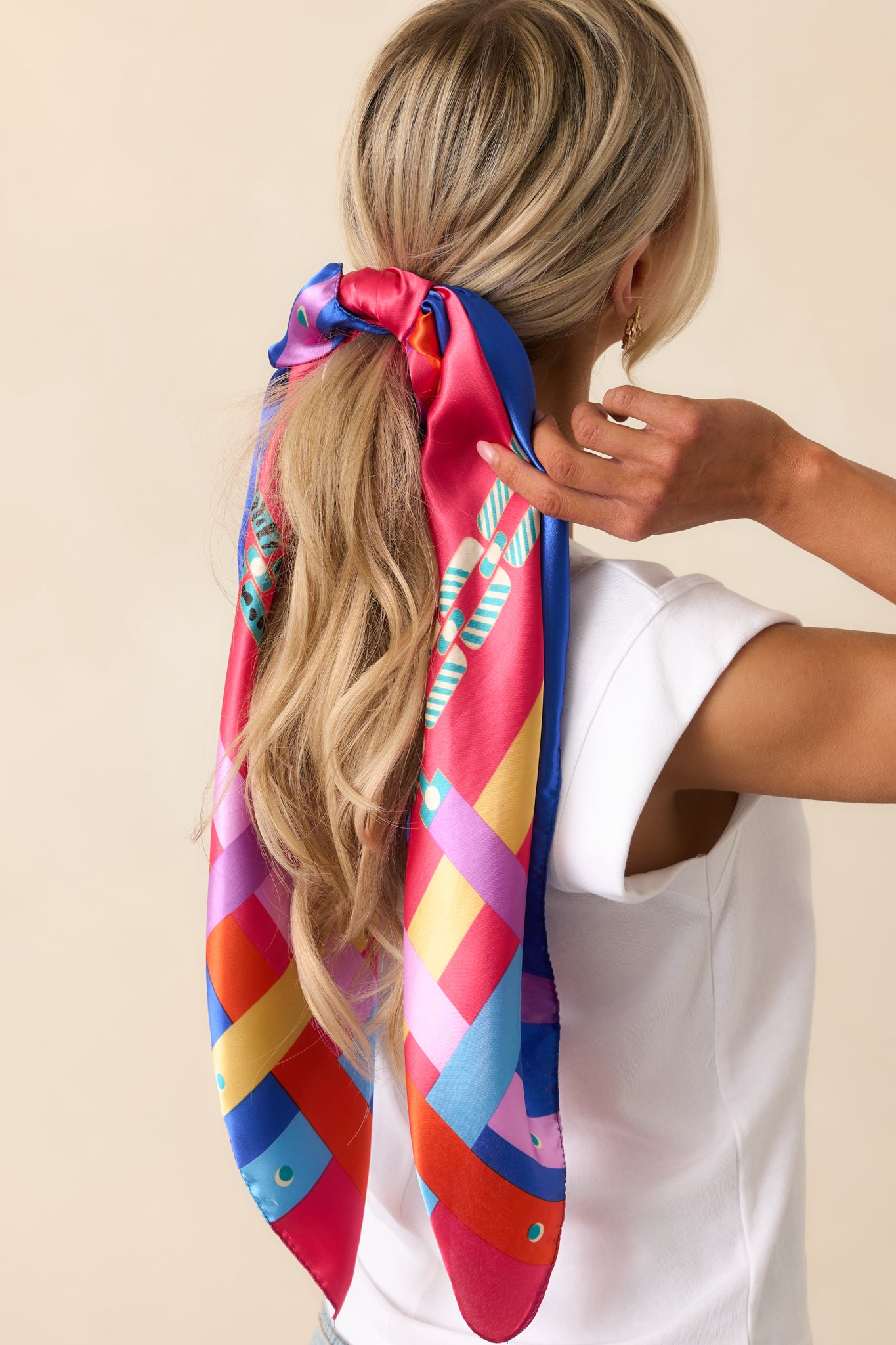 A closer look at the scarf’s fuchsia satin material, where the multi-color chain print and bright accent hues stand out.