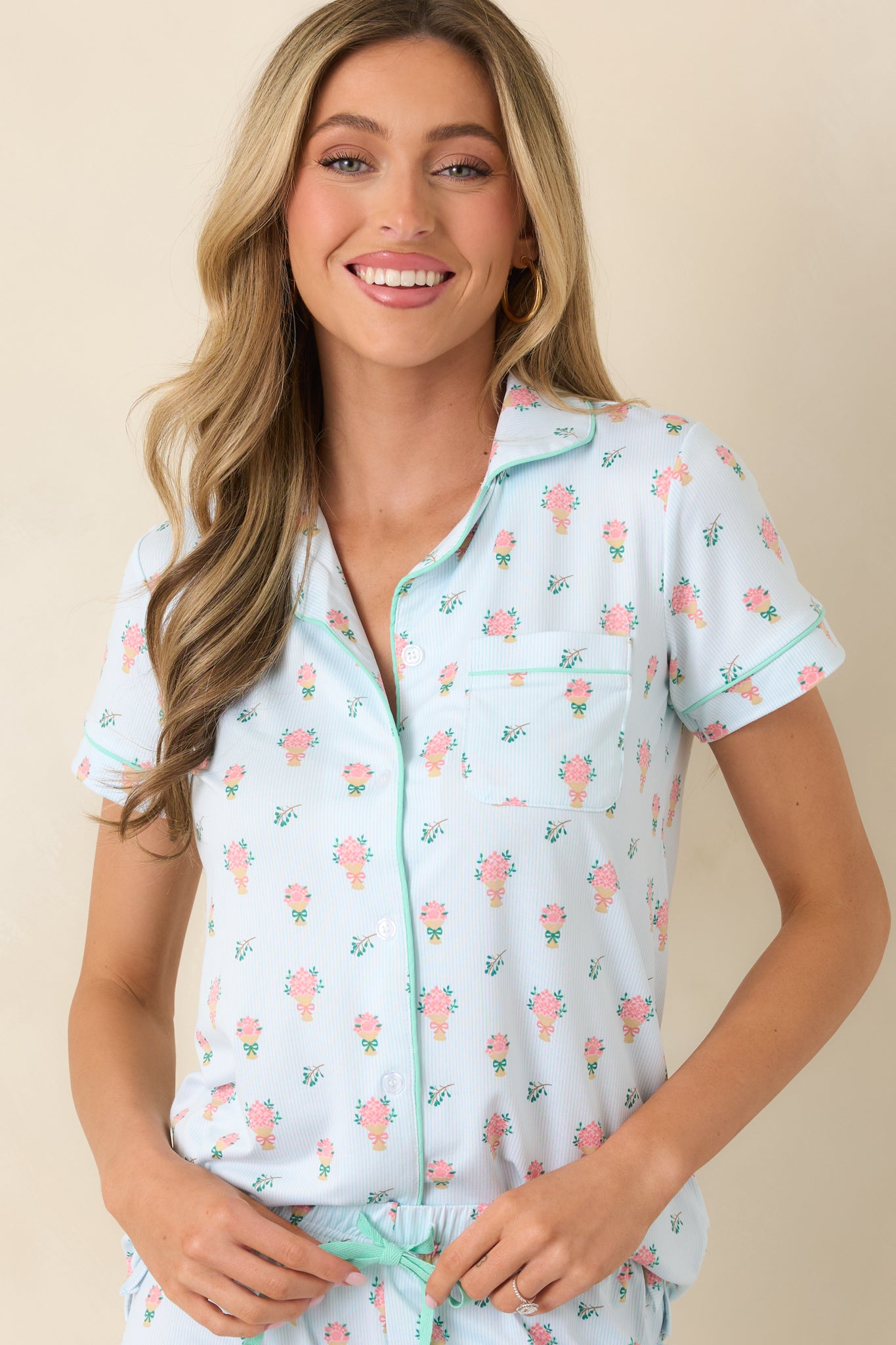 Closer view of the button-front closure framed by contrast piping against the soft green floral fabric.