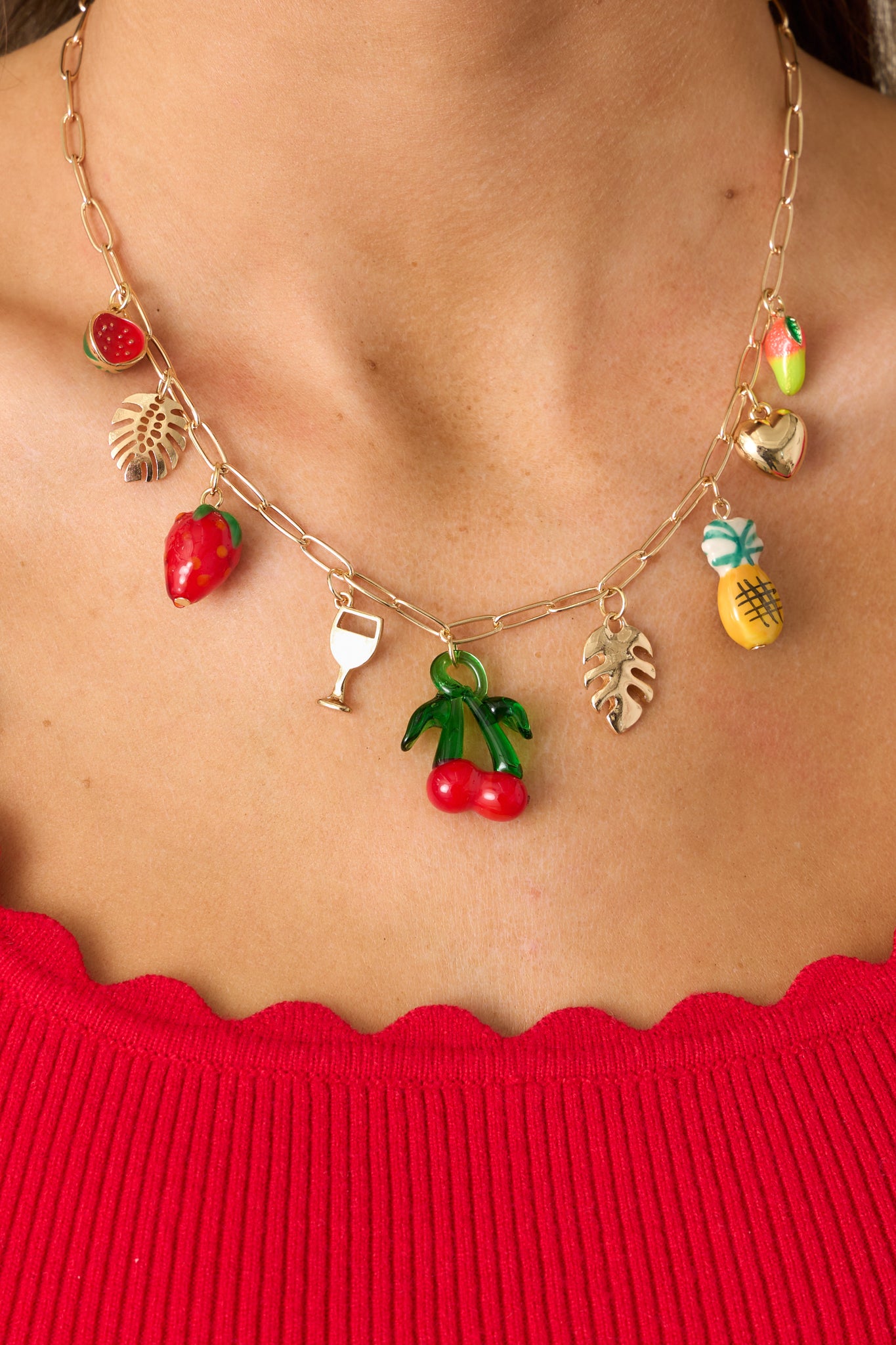 A closer view of the necklace, highlighting the intricate gold leaf charms and the vibrant, multi-colored fruit charms.