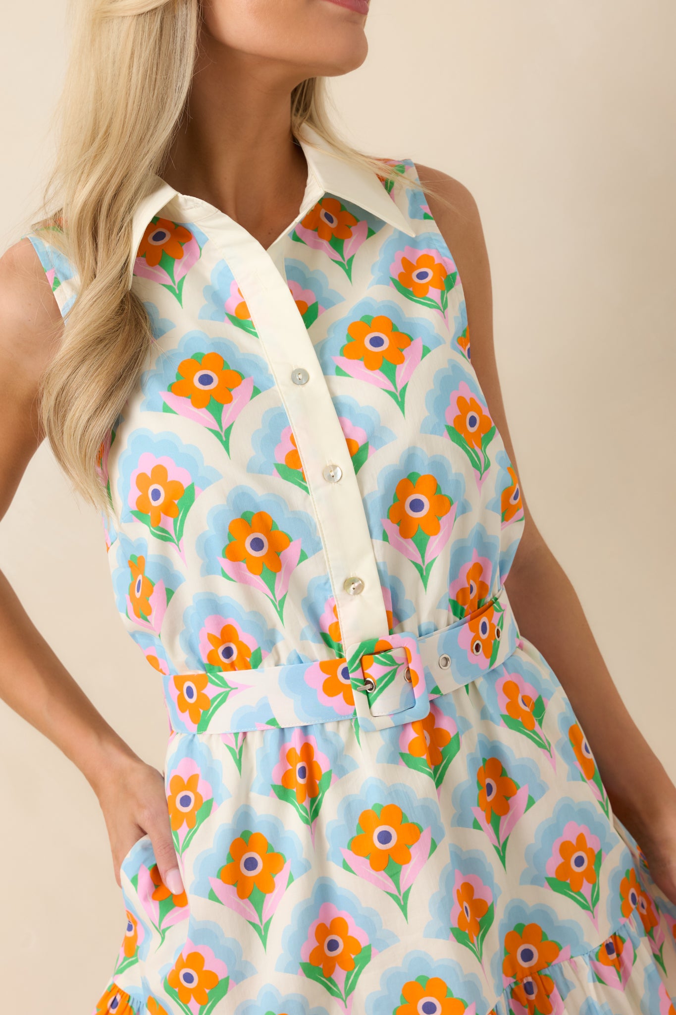 Close-up of the orange and light blue floral print, functional buttons, and collared neckline.