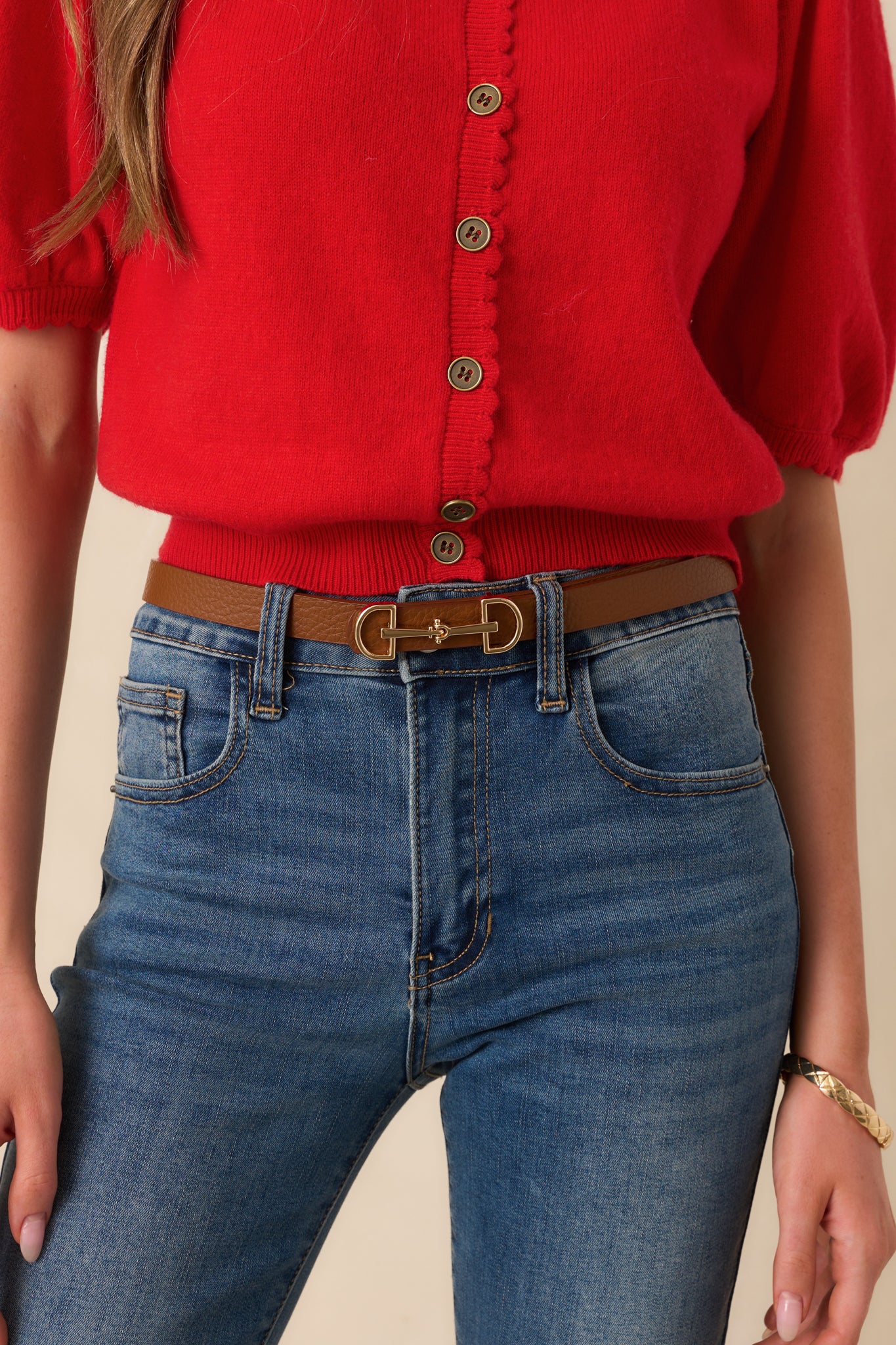 A cropped view of the cognac brown belt wrapped at the waist, showing the textured faux leather material.