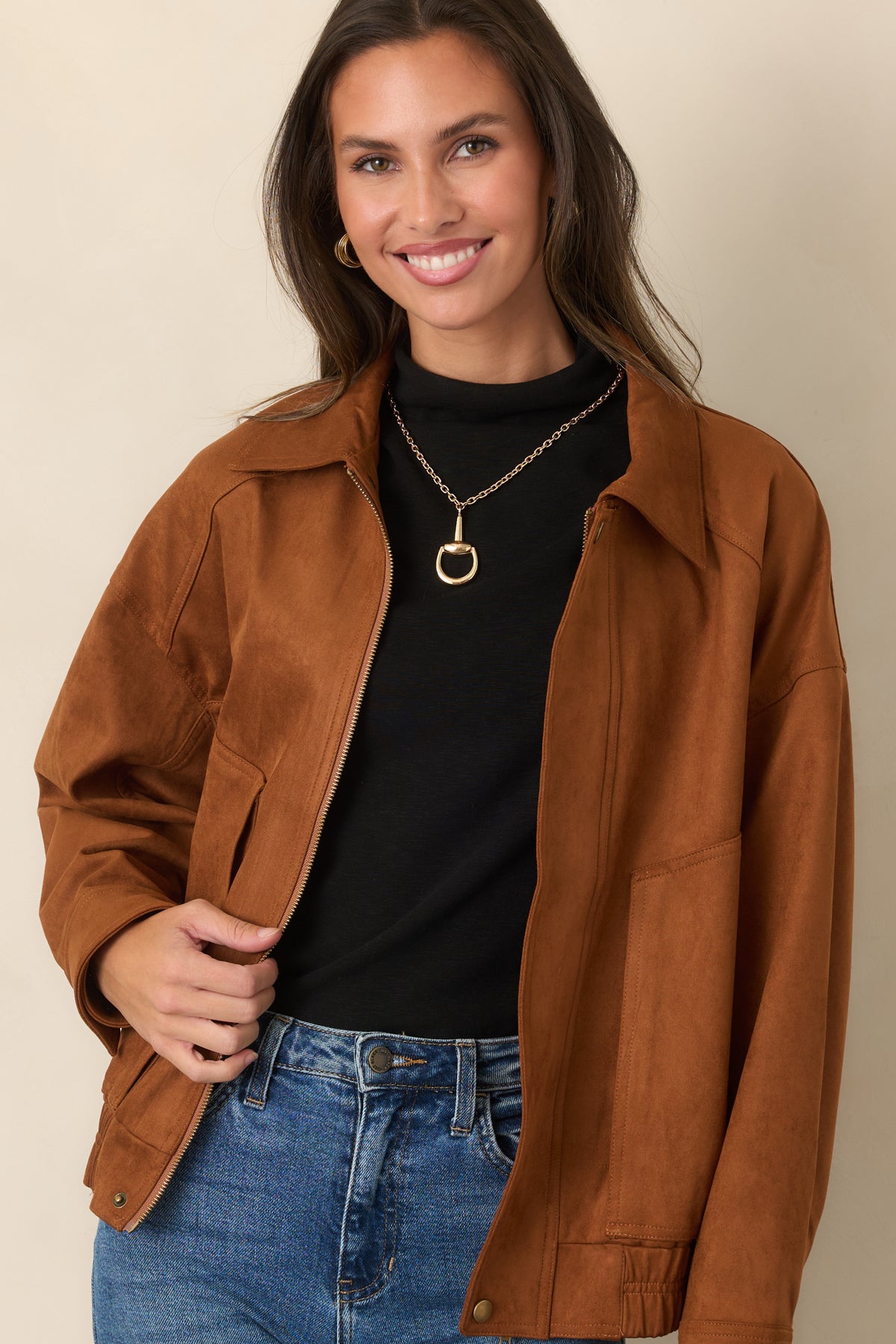 Cognac faux suede bomber jacket highlighting the front pocket, zip closure, and relaxed sleeve shape.