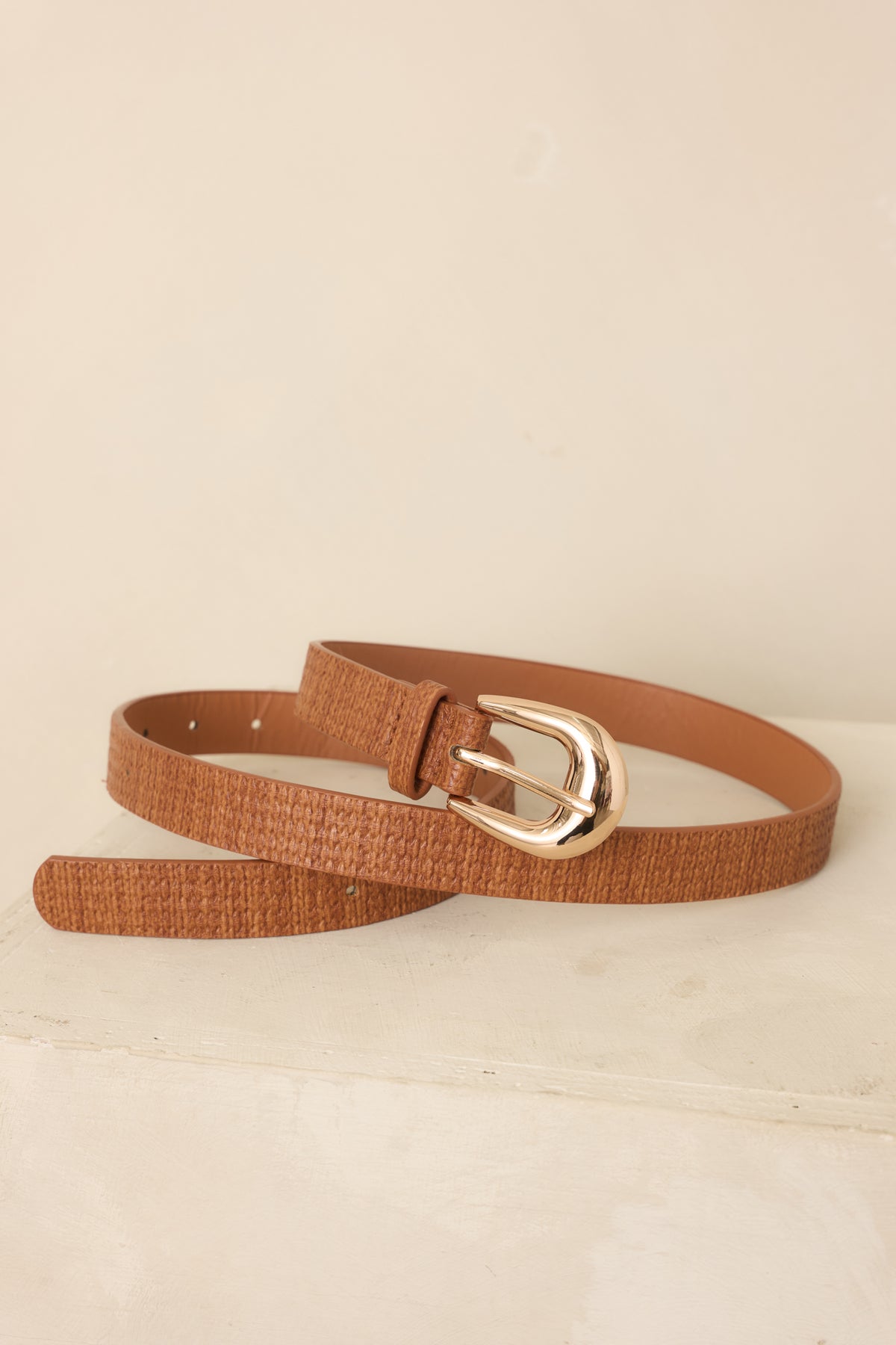Cognac brown woven-texture belt showcasing the dimensional faux leather finish, gold-tone buckle, and evenly spaced punched holes for an adjustable fit.