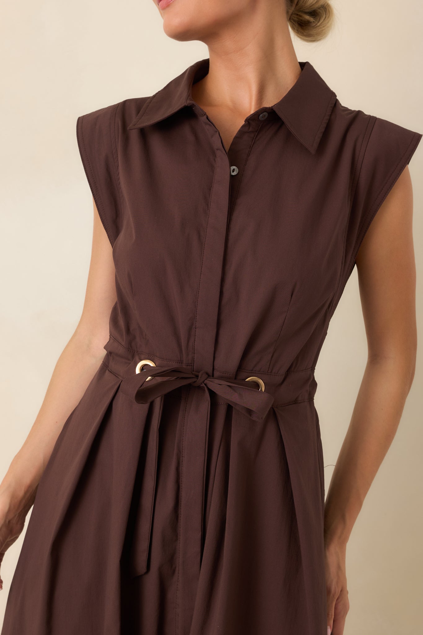 Close-up detail of the collared neckline, concealed buttons, and gold-tone belted waist accents.