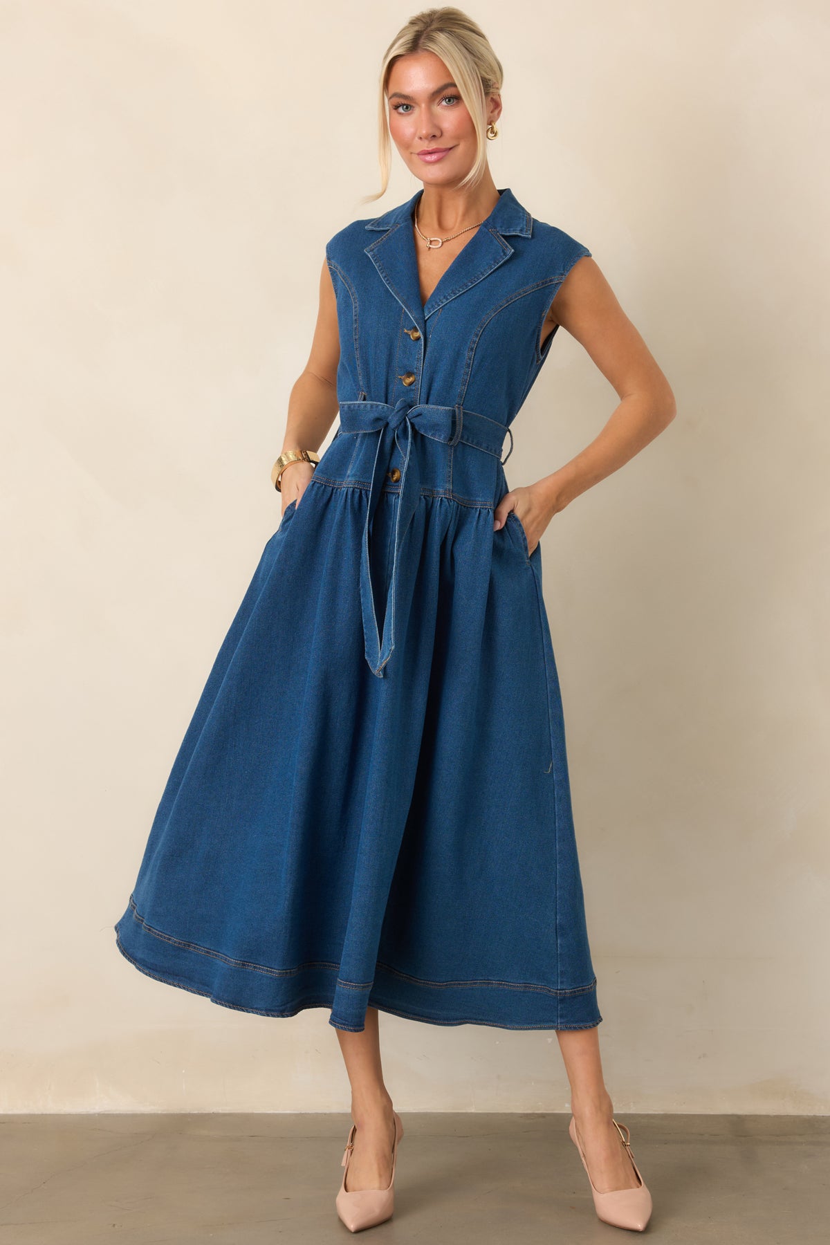 Collared denim midi dress featuring a sleeveless cut, polished gold-tone hardware, adjustable tie waist, and streamlined midi-length silhouette.
