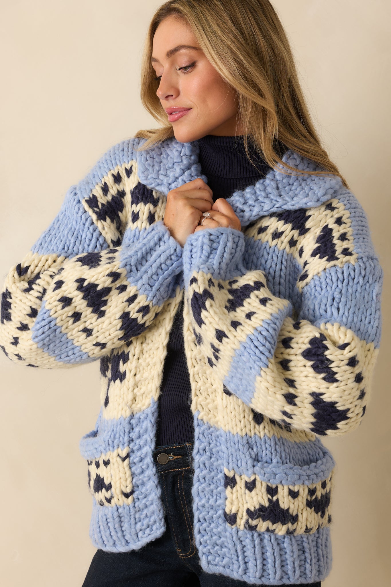 Close crop showing the colorblock pattern, front patch pocket, and thick ribbed trim on the chunky knit cardigan.
