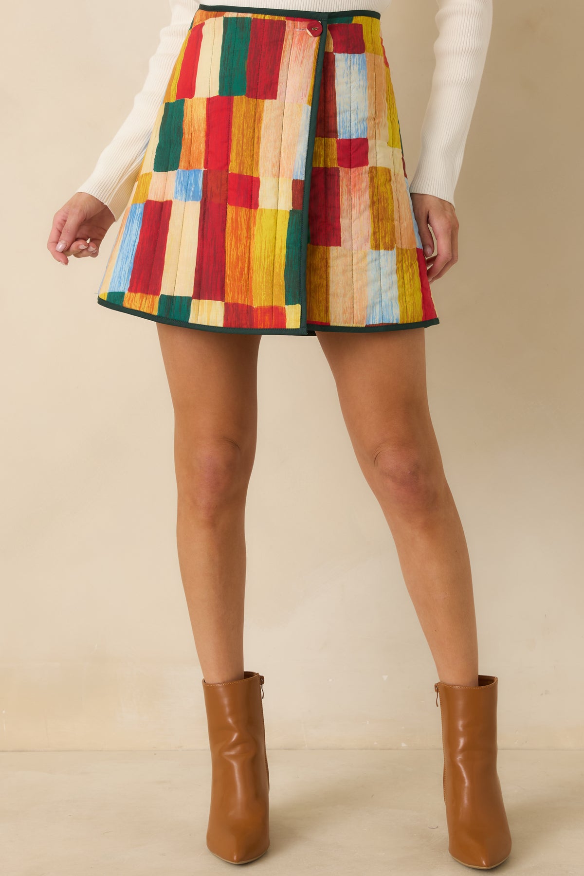 Colorful A-line skirt featuring quilted stitching and a button closure securing the wrap front.