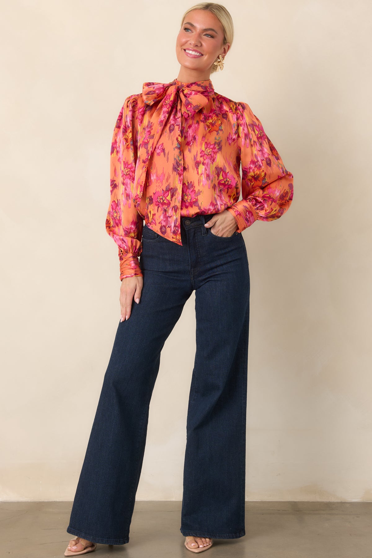 Colorful polyester satin blouse featuring a dramatic tie neckline, lightly gathered shoulders, long balloon sleeves, and buttoned cuffs with a soft sheen.