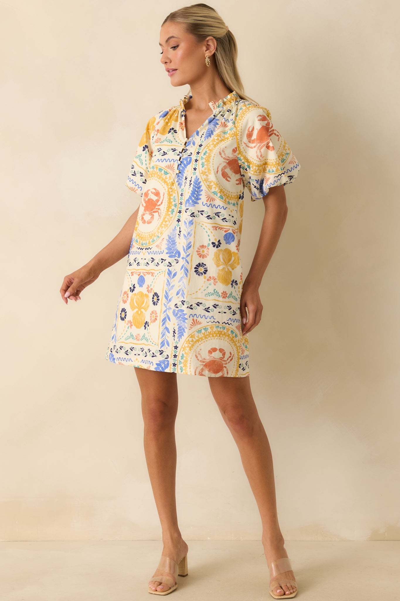 Cotton shift mini dress featuring coral, blue, yellow, and green patchwork artwork with decorative buttons and a stand collar.