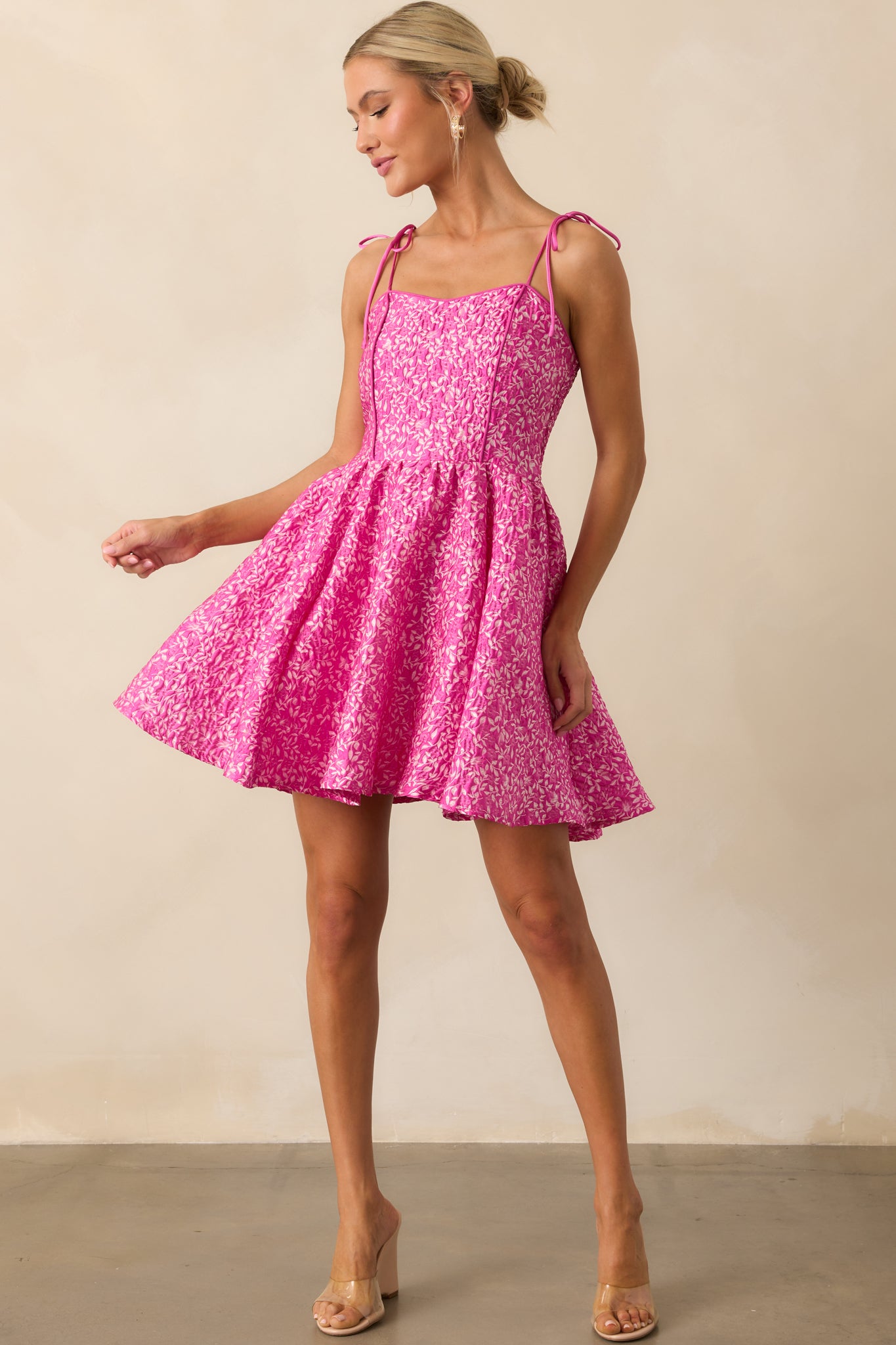 Complete look at the fuchsia floral dress, showcasing its bright color, short hemline, and feminine cut.