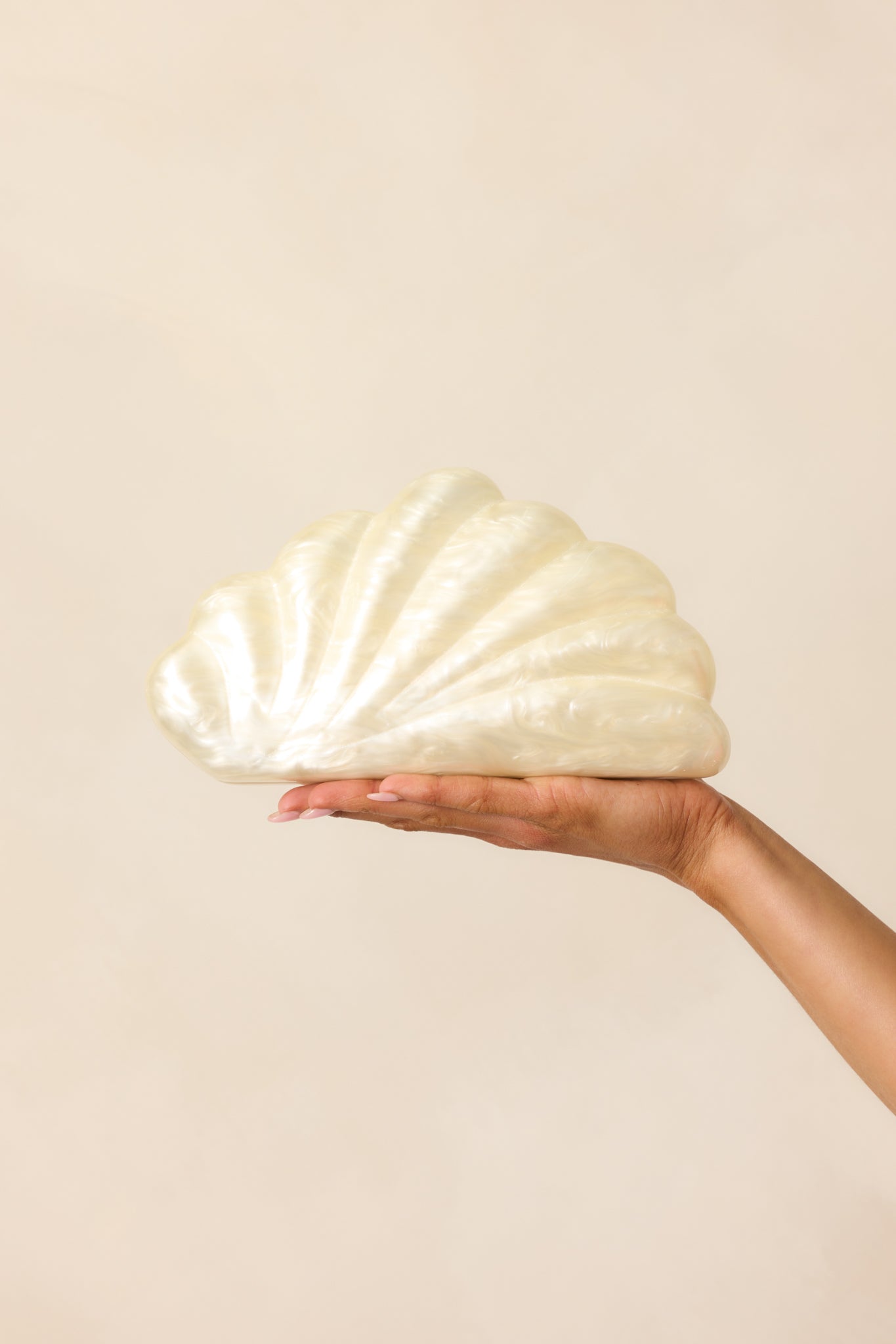 A complete view of the ivory clutch emphasizing its pearlescent texture and the fine detailing of the shell ridges.