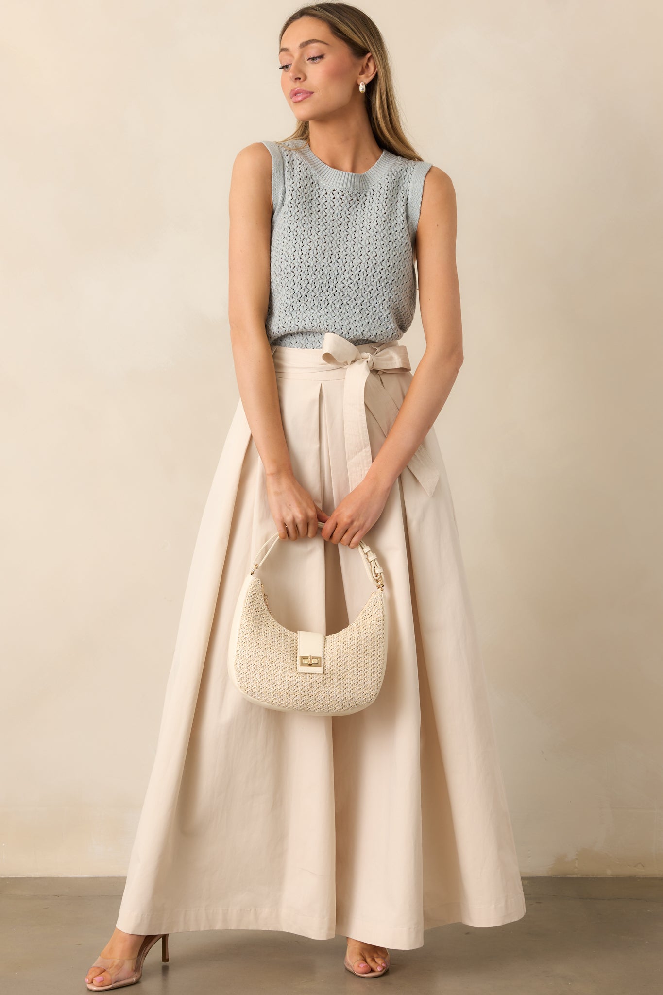 A complete view of the wide-leg ecru pants with a self-tie belt, highlighting the draped fit and structured waistband.