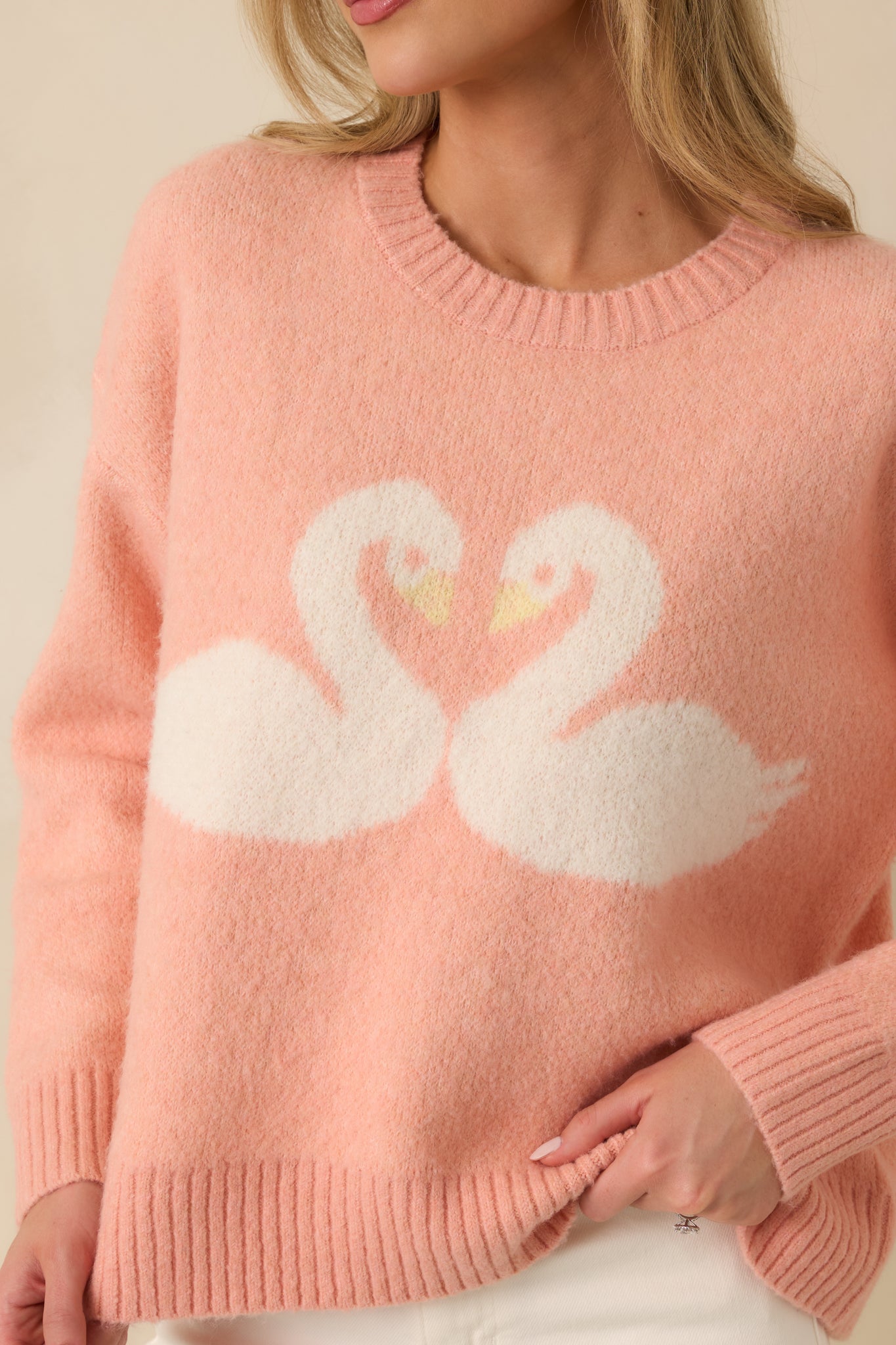 Detailed view of the coral knit fabric with ribbed trim and the intarsia swan motif forming a heart-inspired pattern.
