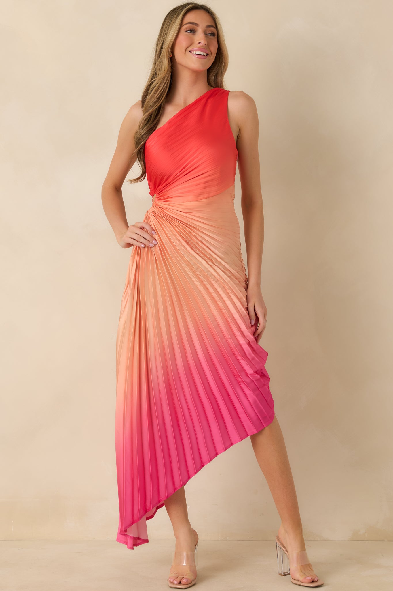 Front view of a coral ombre maxi dress with an asymmetric one-shoulder neckline, fitted bodice, and flowing pleated skirt.