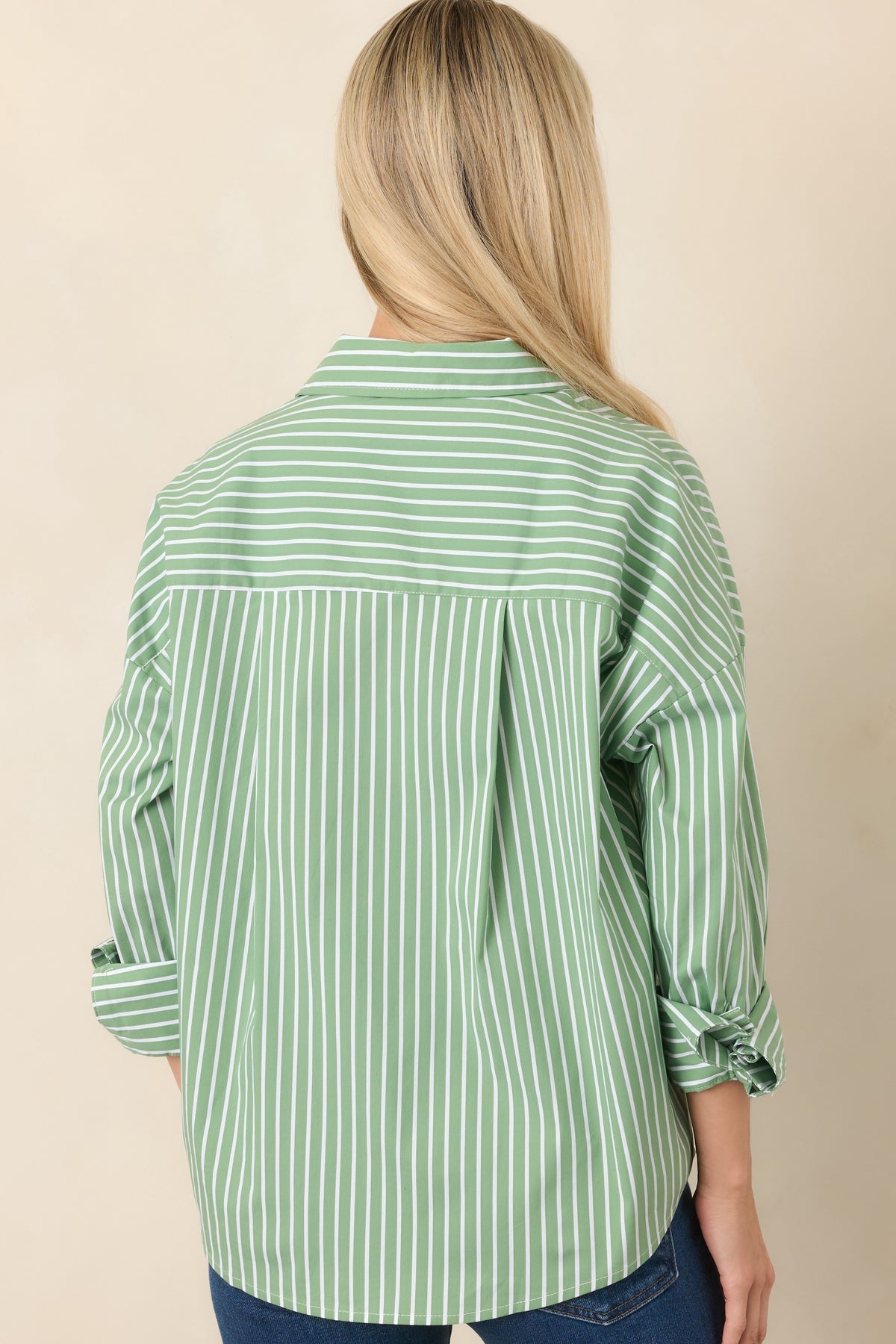 Rear view of the cotton-blend button-up top showing the back box pleat, drop shoulders, long sleeves, and relaxed silhouette.
