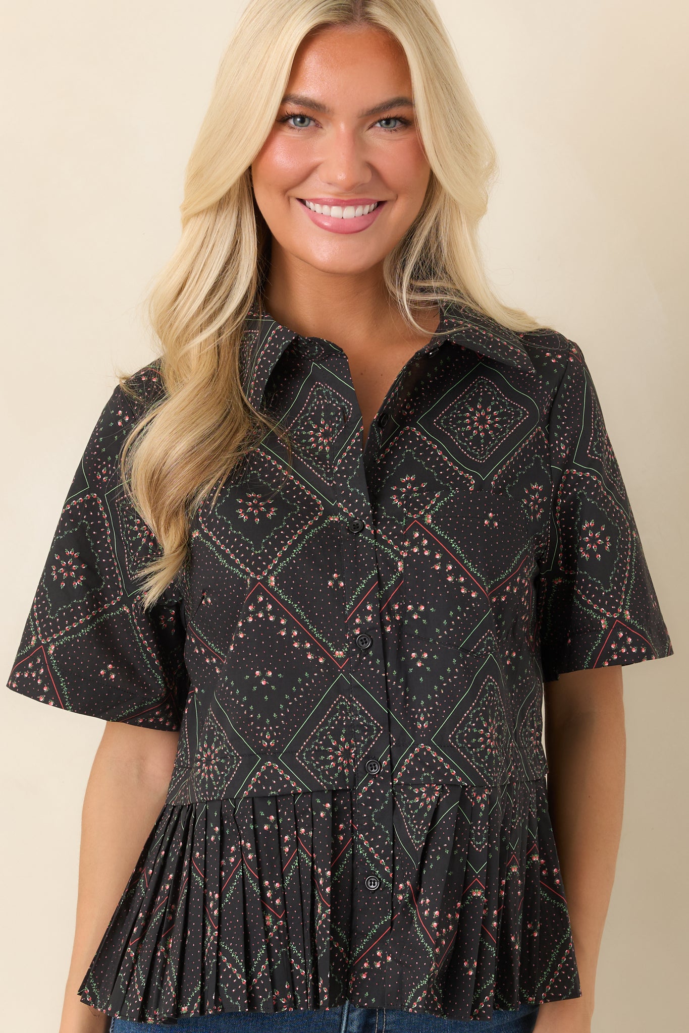 Short sleeves and sharply pleated peplum hem create a flattering silhouette on this black floral print cotton blouse.