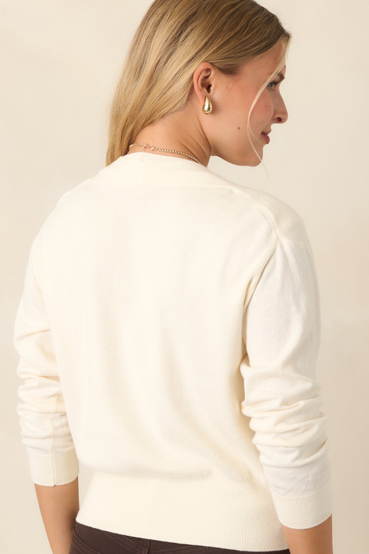 Rear of the layered cotton-cashmere sweater showing the sleeveless knit base, long sleeves, smooth back, and wide ribbed hem.