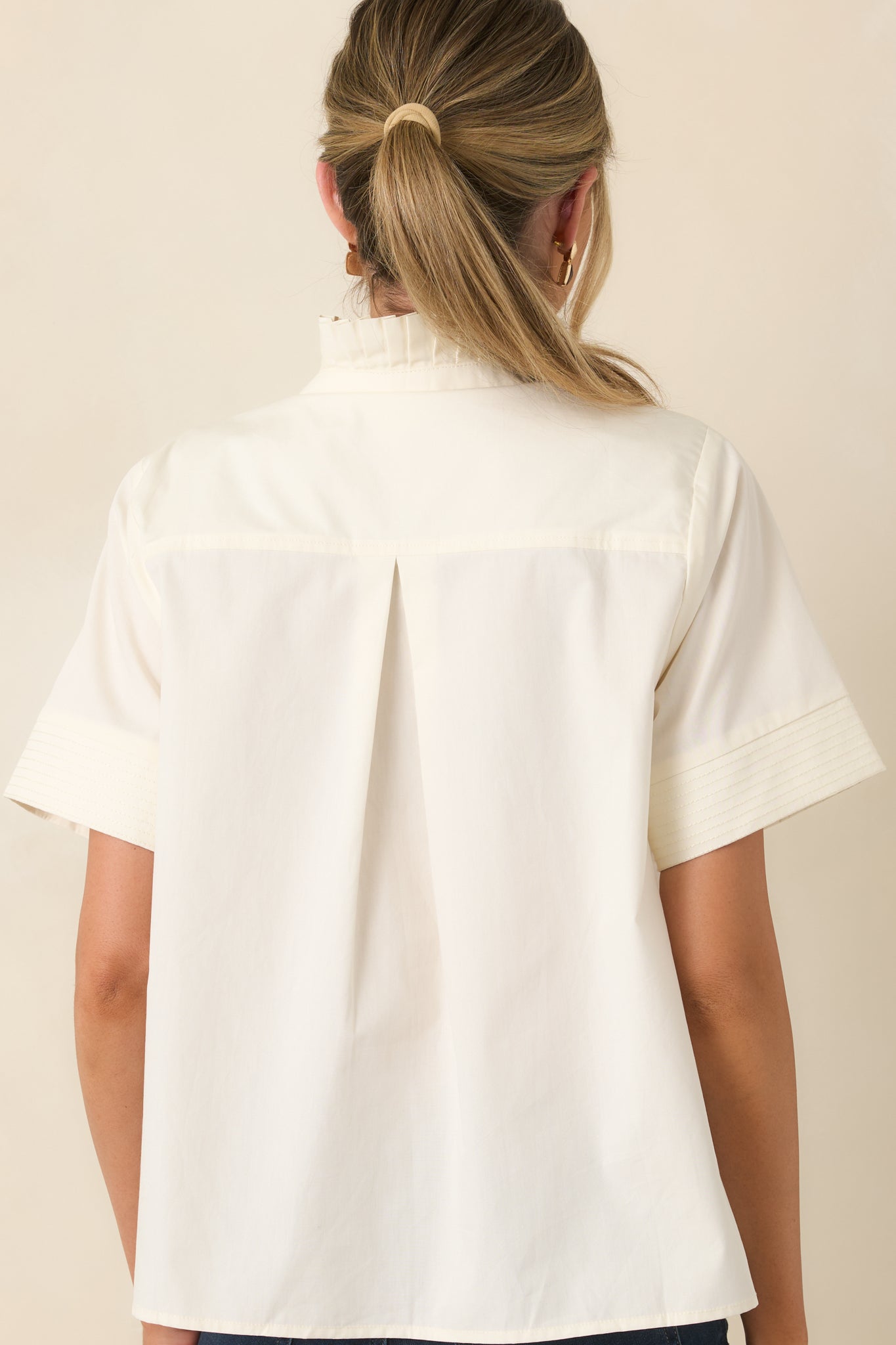 Rear view of the cotton top featuring a center back pleat, short sleeves, and a relaxed draped silhouette.