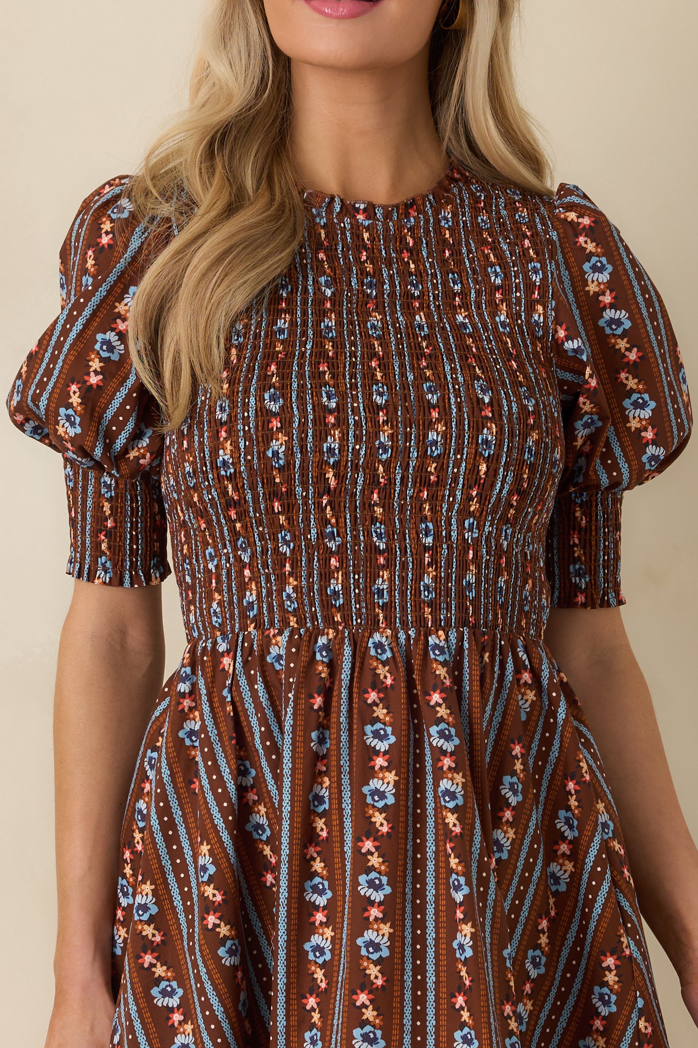 Close-up detail of the cotton dress showing delicate blue and orange florals arranged in vertical stripes against brown.
