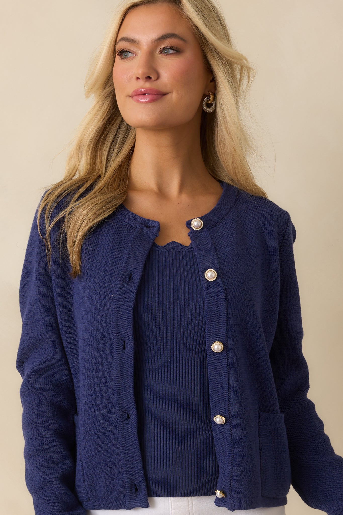 Cotton knit cardigan featuring a crew neckline, pearl-inspired gold-tone buttons, front patch pockets, and long sleeves.
