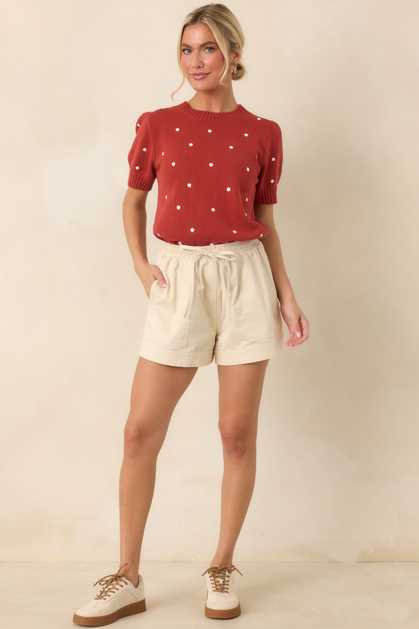 Cotton knit polka dot top showcasing a rust red color, ribbed crew neckline, fitted sleeve cuffs, and a polished ribbed hem.