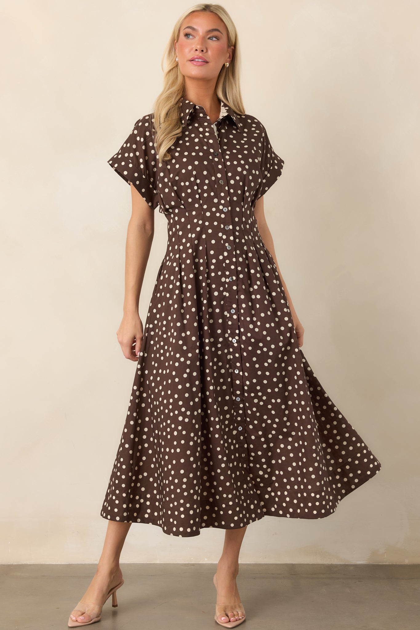 100% cotton midi dress featuring a structured collar, short sleeves, fitted waist, flowing skirt, and ivory polka dot contrast panel along the button placket.