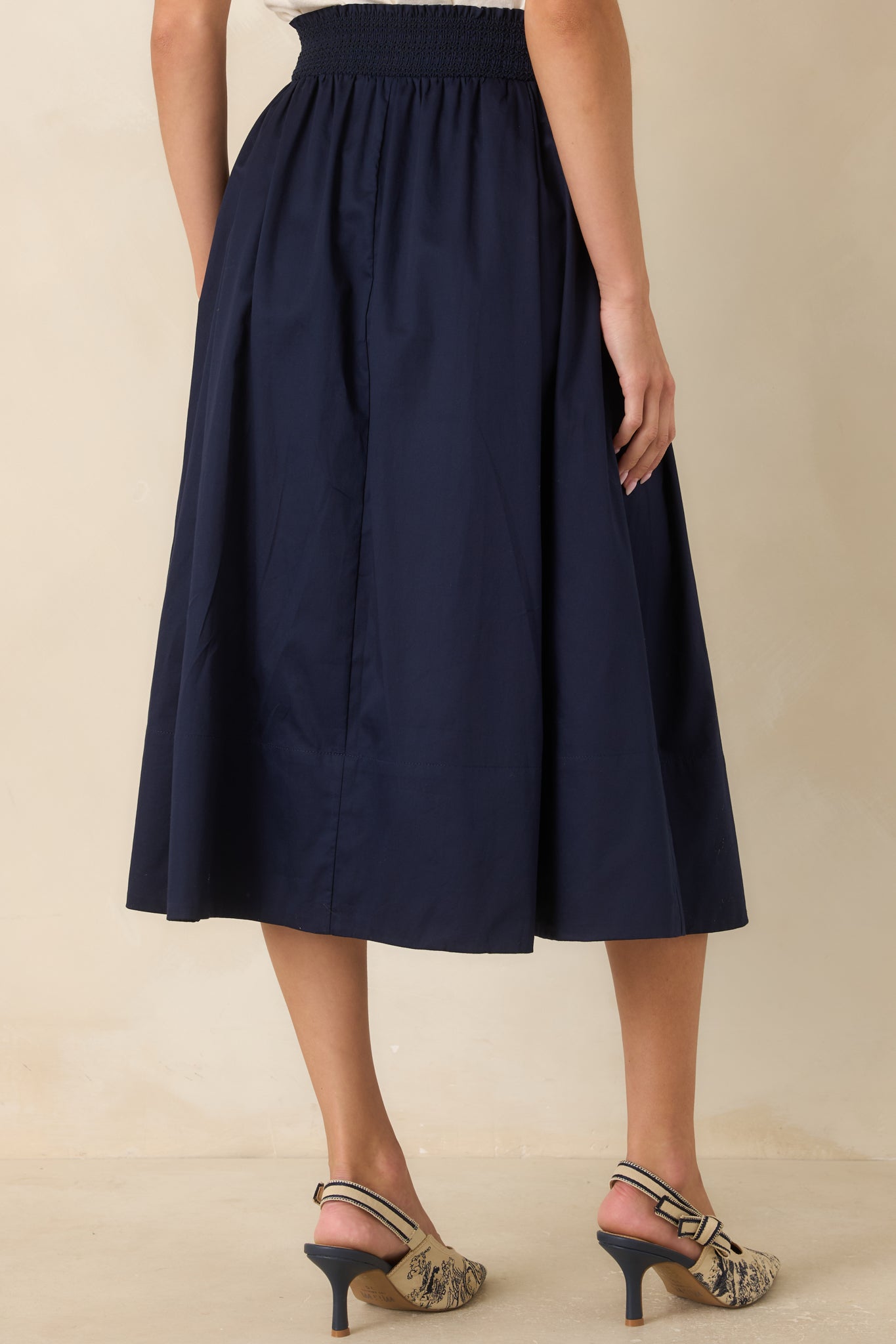 Back view of the cotton midi skirt featuring a smocked waistband and flowing pleated silhouette.