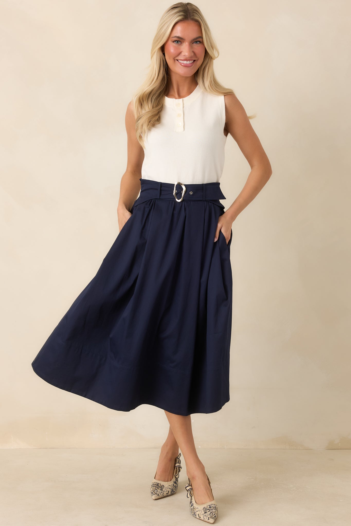 Cotton midi skirt featuring soft pleats, functional side pockets, and an attached belt with a silver sculptural buckle.