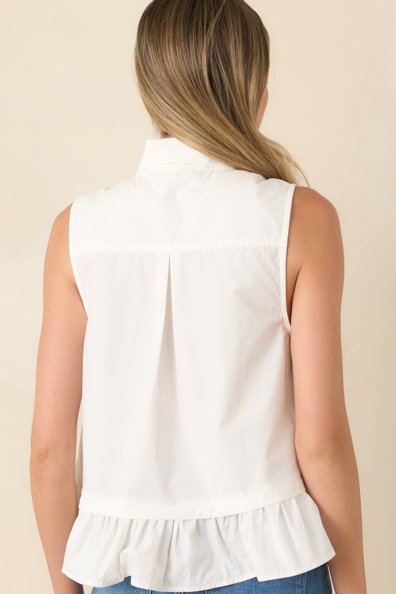 Rear view of the cotton sleeveless top highlighting the relaxed silhouette, gathered ruffle hem, and clean back design.