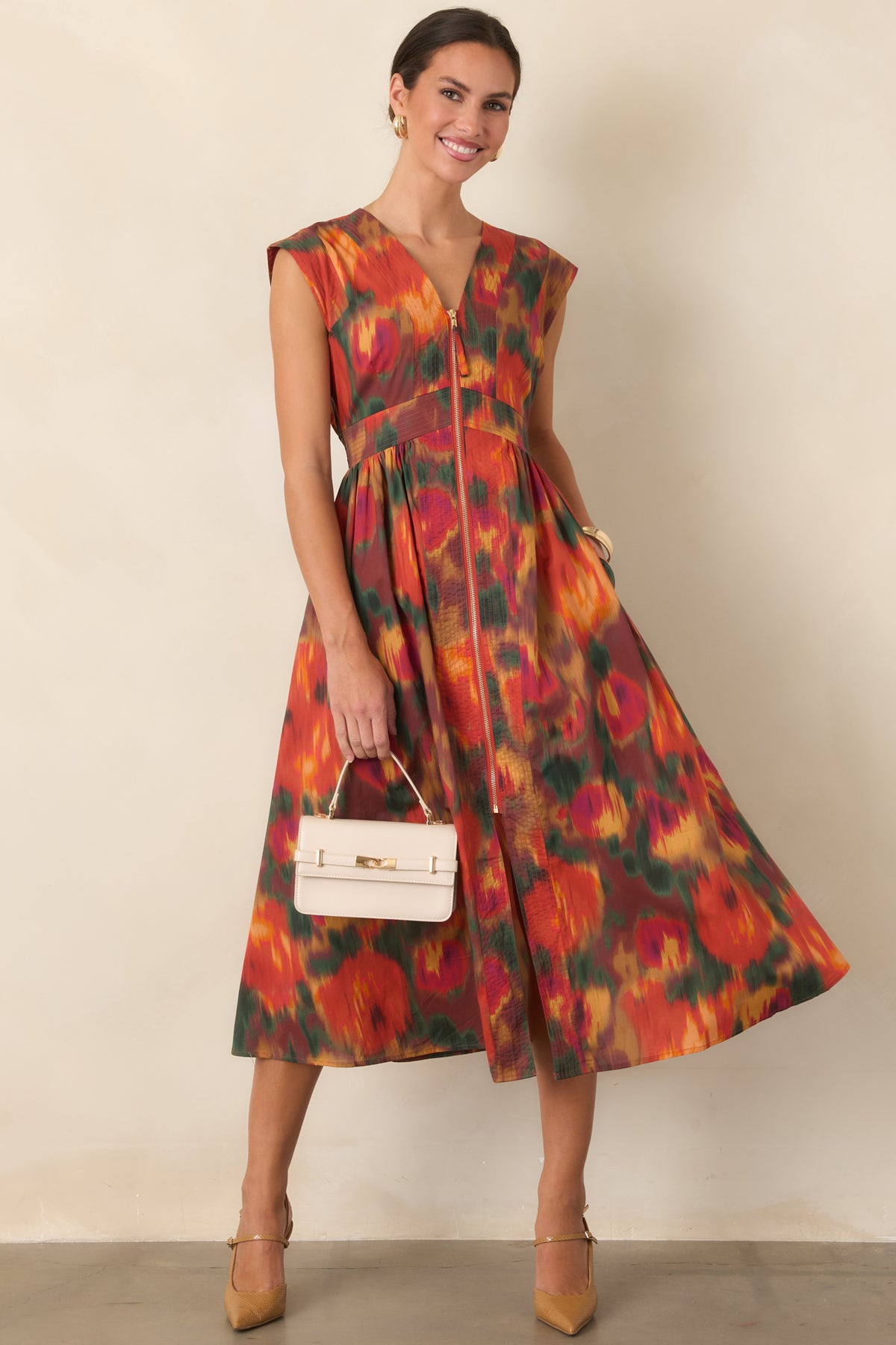 Cotton midi dress showcasing painterly floral blooms in warm rust, orange, green, gold, and berry shades with a defined waist.