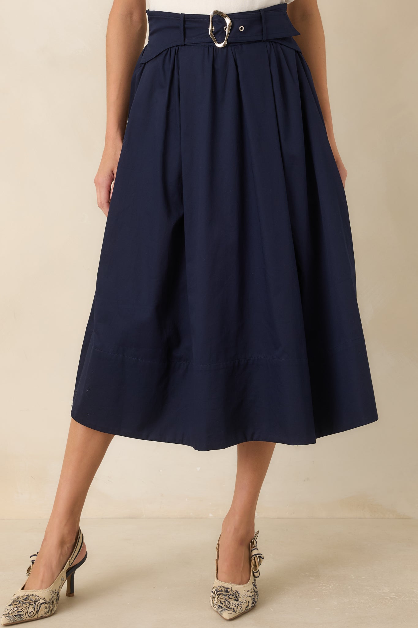 Close view of the cotton skirt showcasing the attached side tabs, silver buckle, and soft pleat detailing.