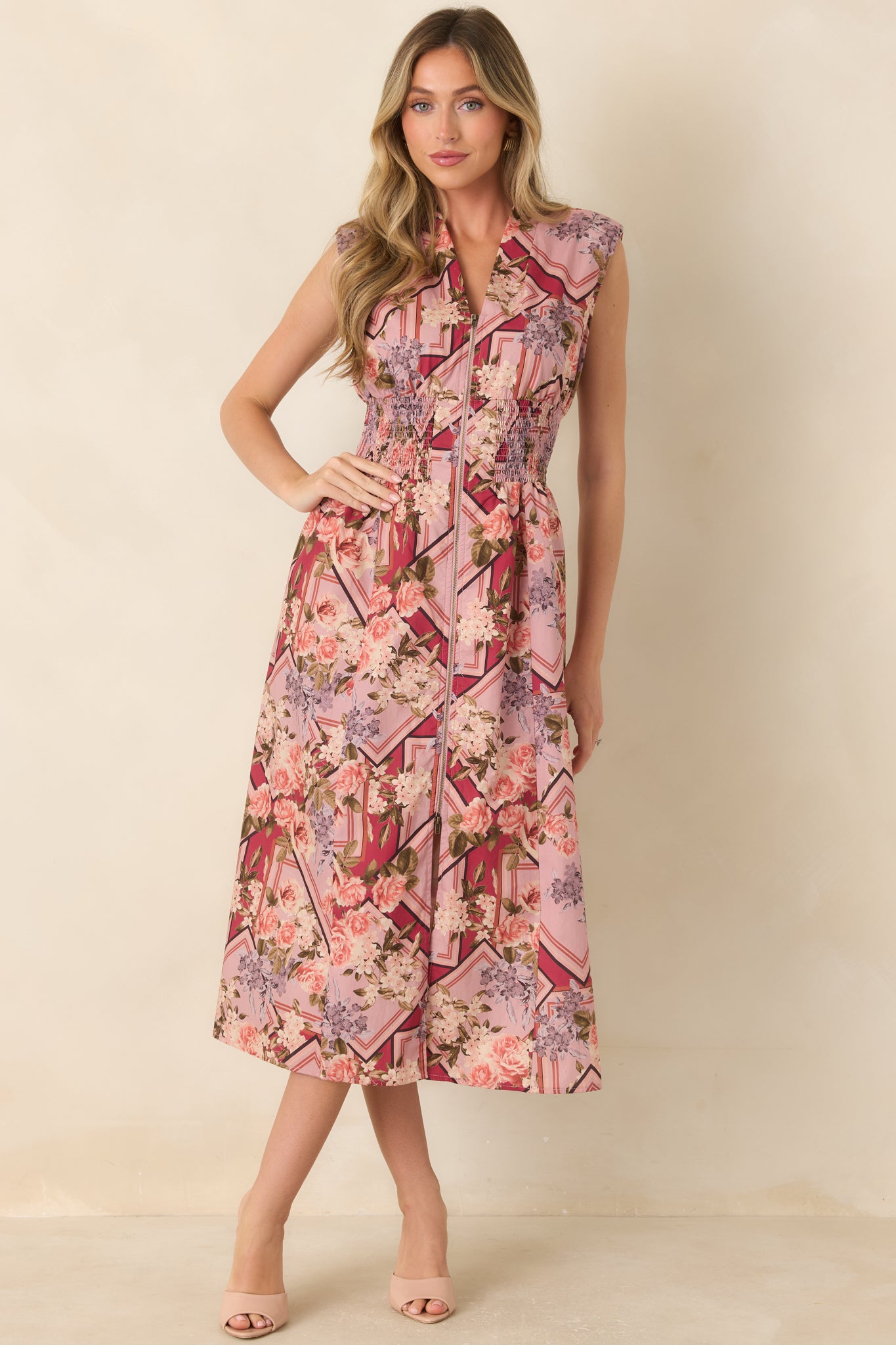 100% cotton midi dress featuring a sleeveless silhouette, V-neckline, full front zipper, smocked waist, and flowing skirt with side pockets.