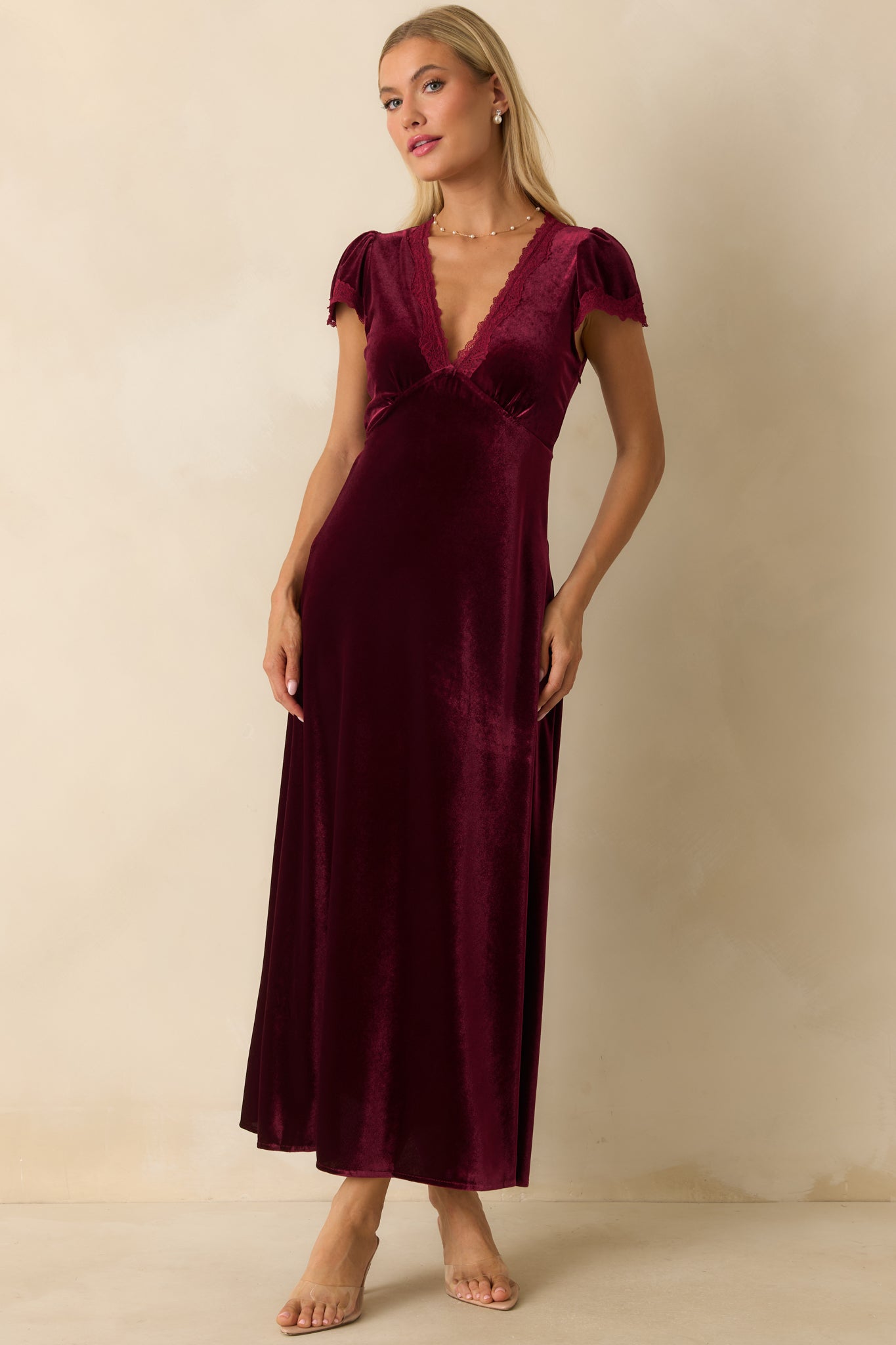 Cranberry red velvet maxi dress with V-neckline trimmed in lace, short flutter sleeves, empire waist, and flowing A-line skirt.