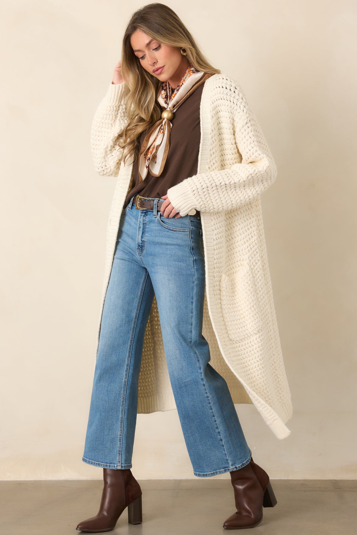 Long cream duster cardigan showcasing a soft chunky knit texture, roomy sleeves, ribbed cuffs, and an effortless open-front design.