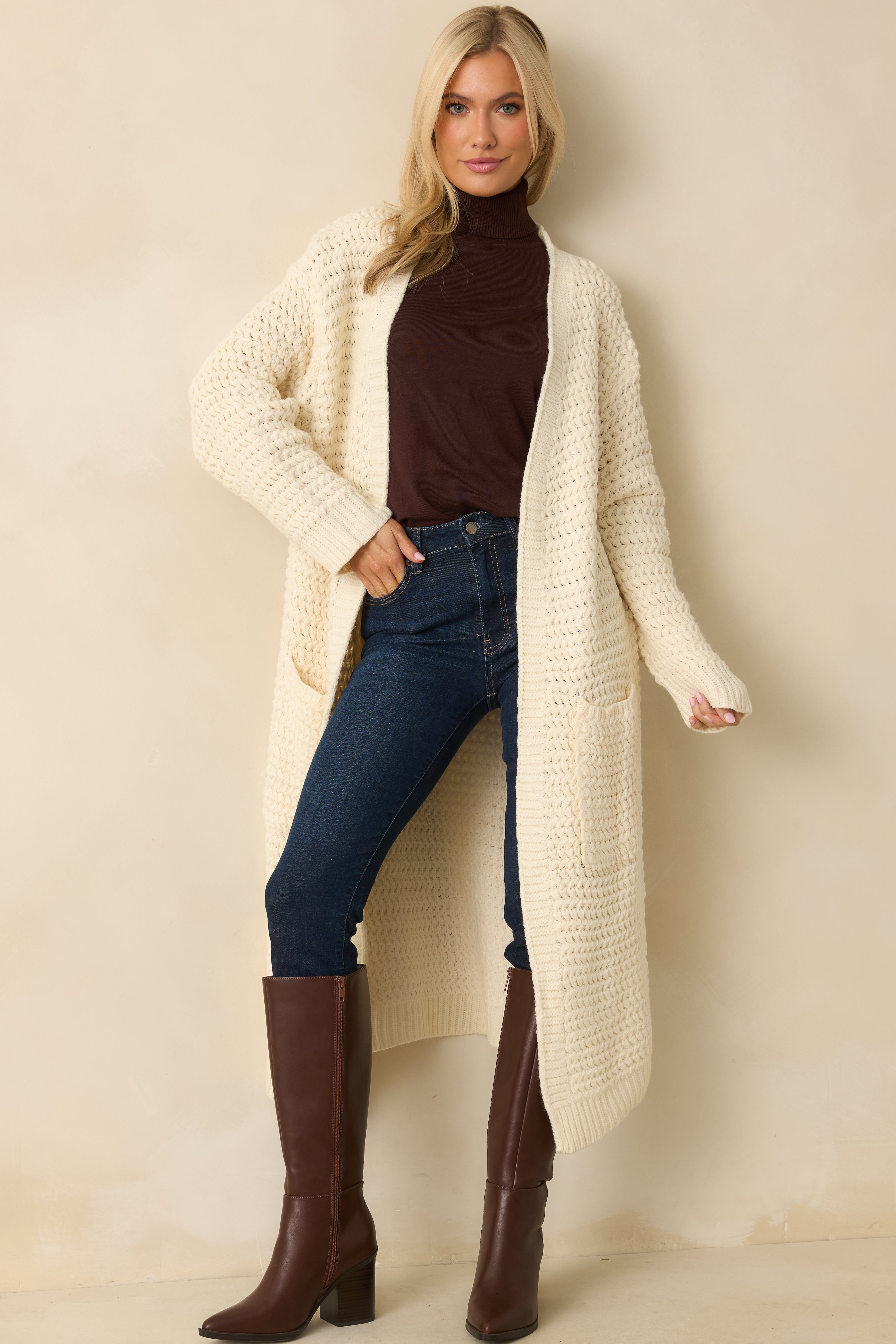 Front view of the cream knit duster cardigan featuring an open front and long sleeves with ribbed cuffs in a chunky textured knit.