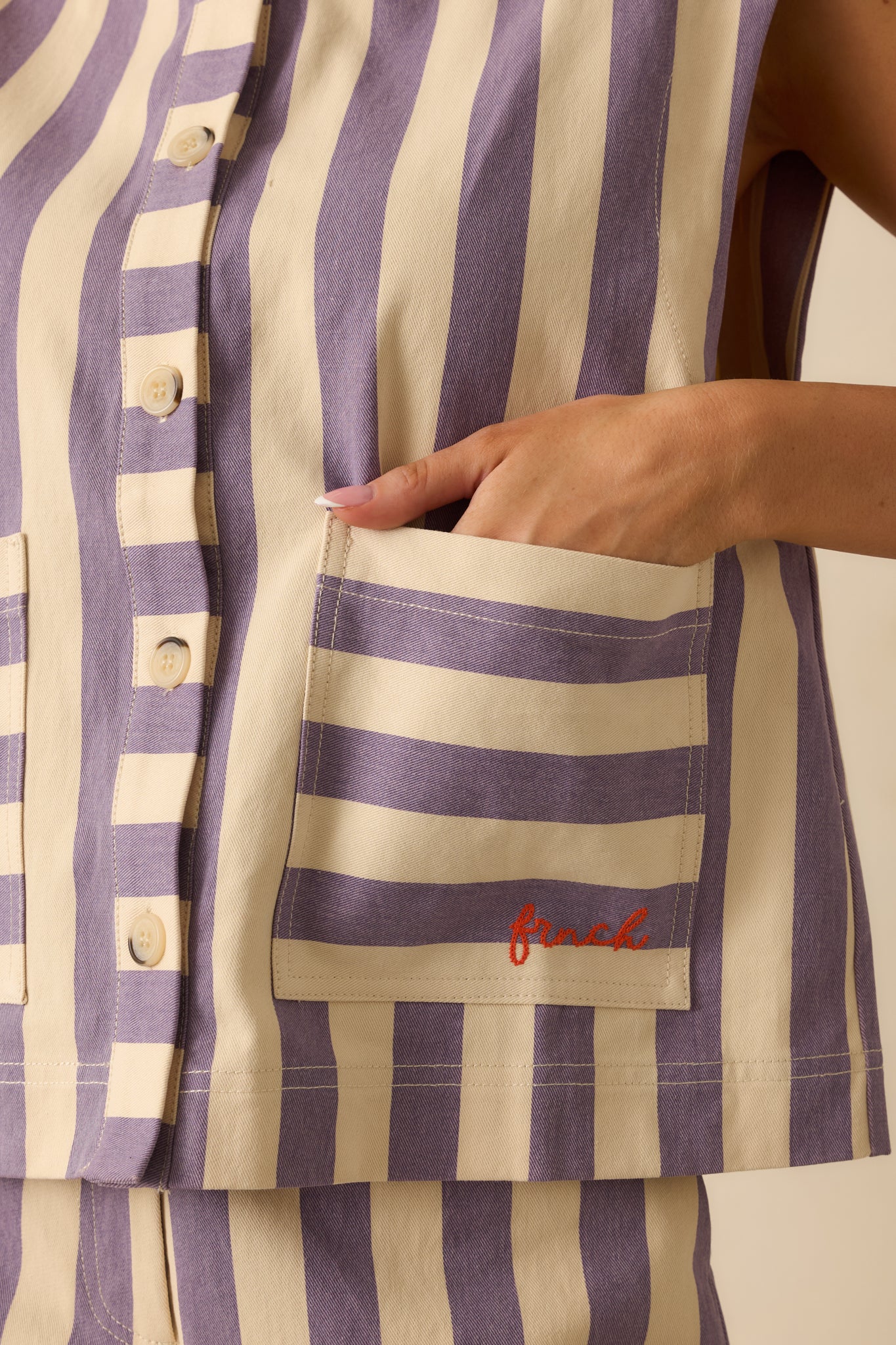 Close-up of the cream and lilac striped fabric, button closure, and patch pocket craftsmanship.