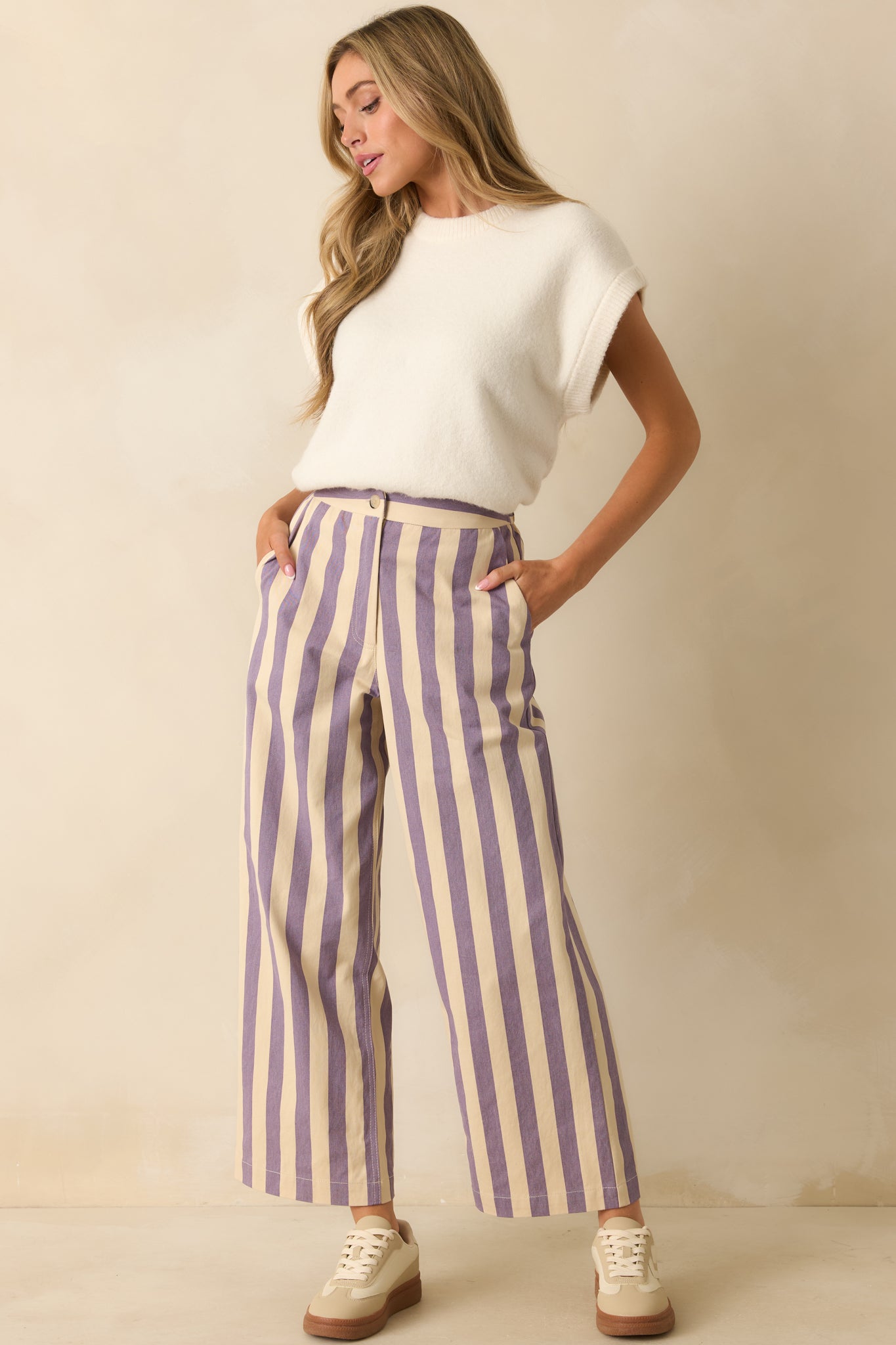 Cream and lilac vertical stripe pants styled to highlight their structured waist and relaxed drape.
