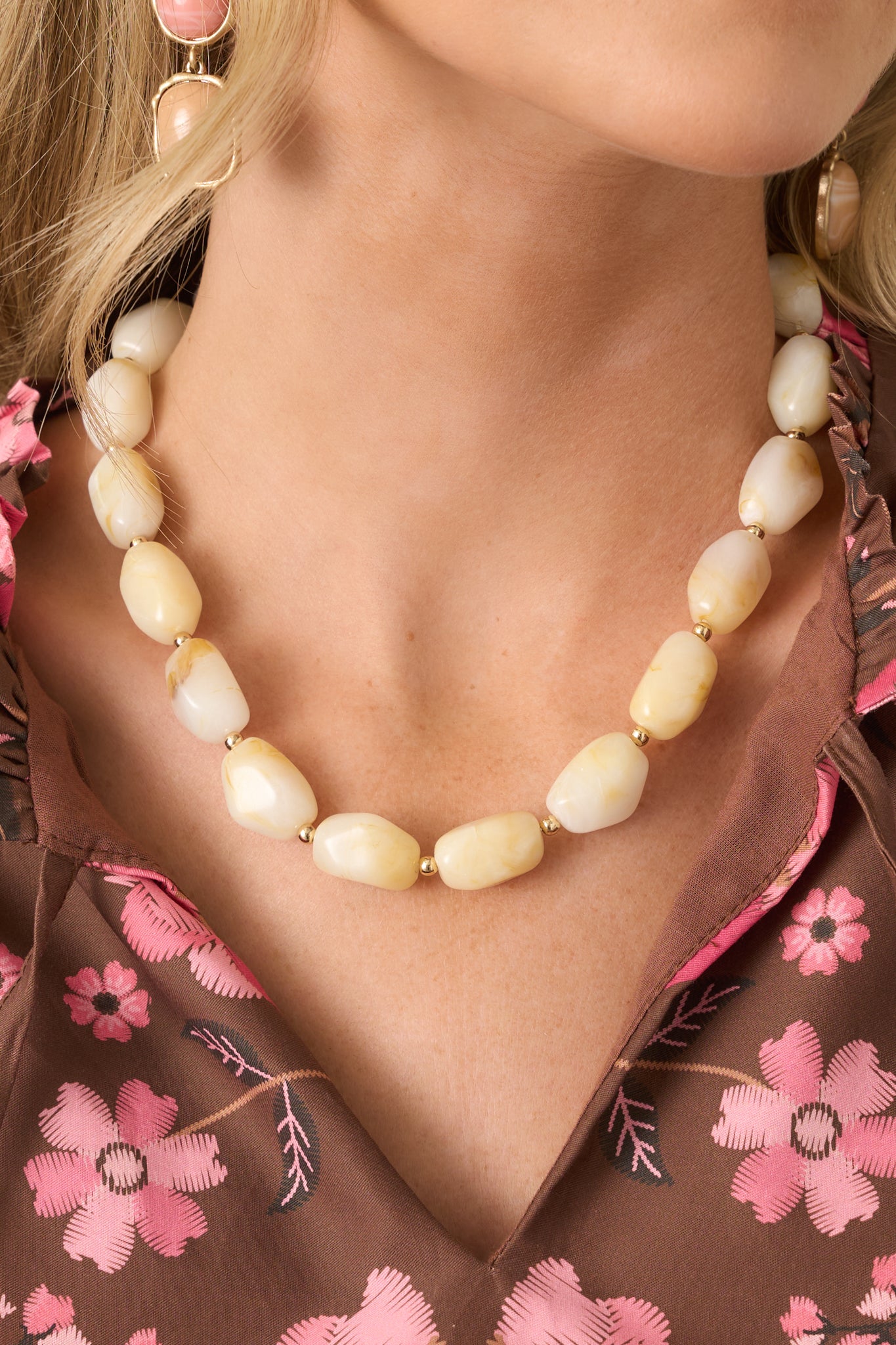 Close-up of the necklace’s marbled cream resin beads and polished gold-tone spacer beads, highlighting their organic shapes and varied textures.
