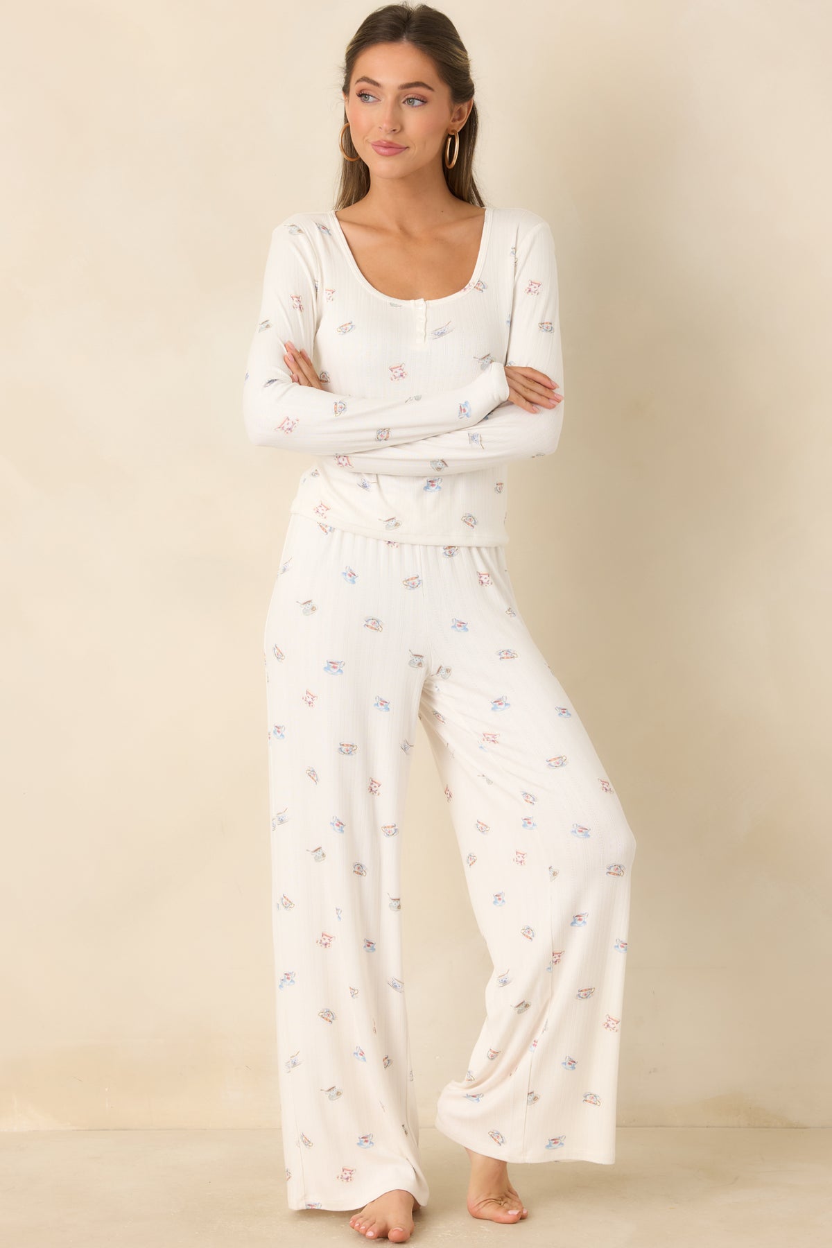 Cream pointelle knit pants featuring scattered teacup motifs and an elastic waistband.