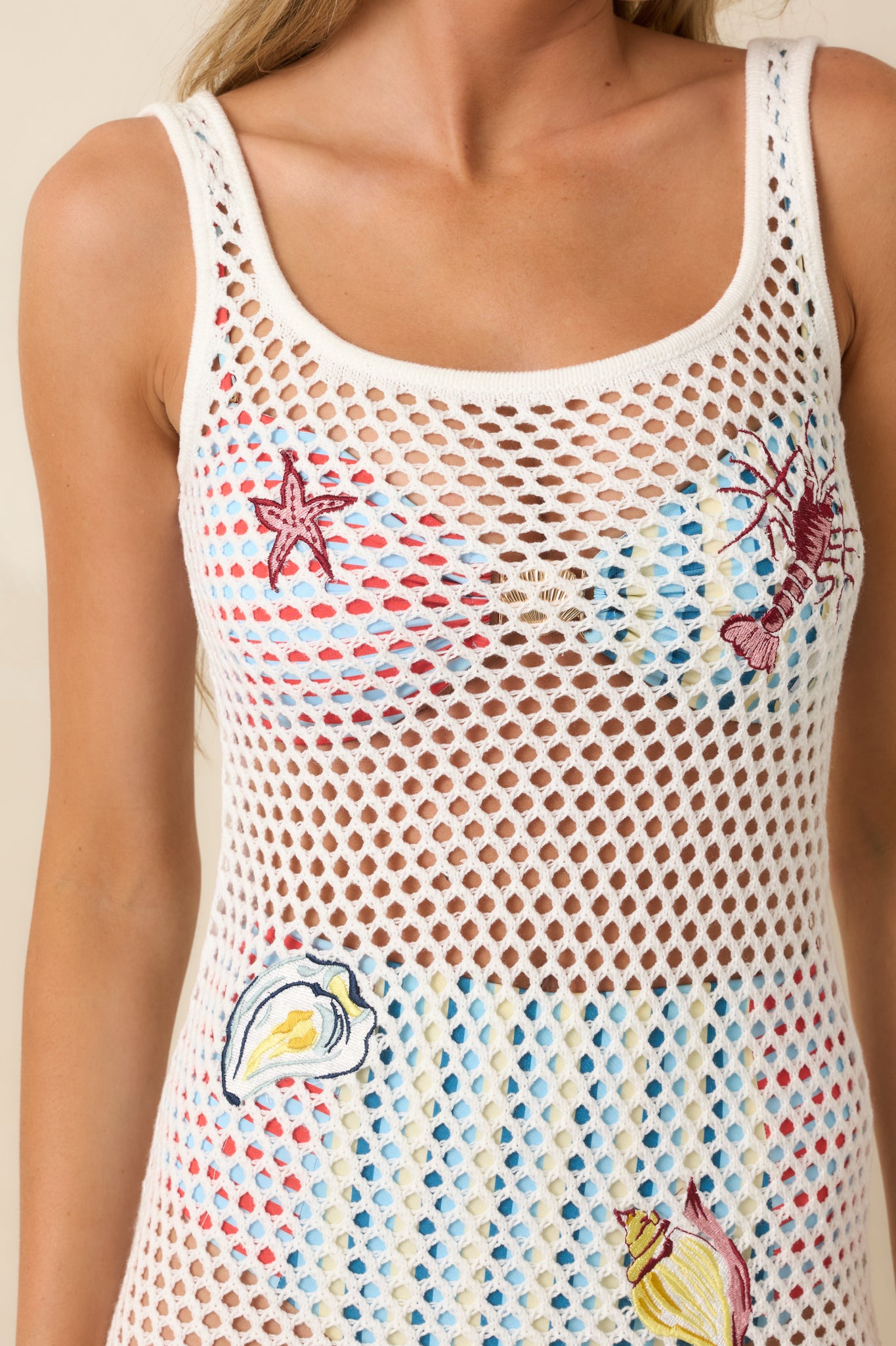 Close-up of the crochet mini dress featuring the textured knit pattern, embroidered shells, and colorful sea-inspired stitching.
