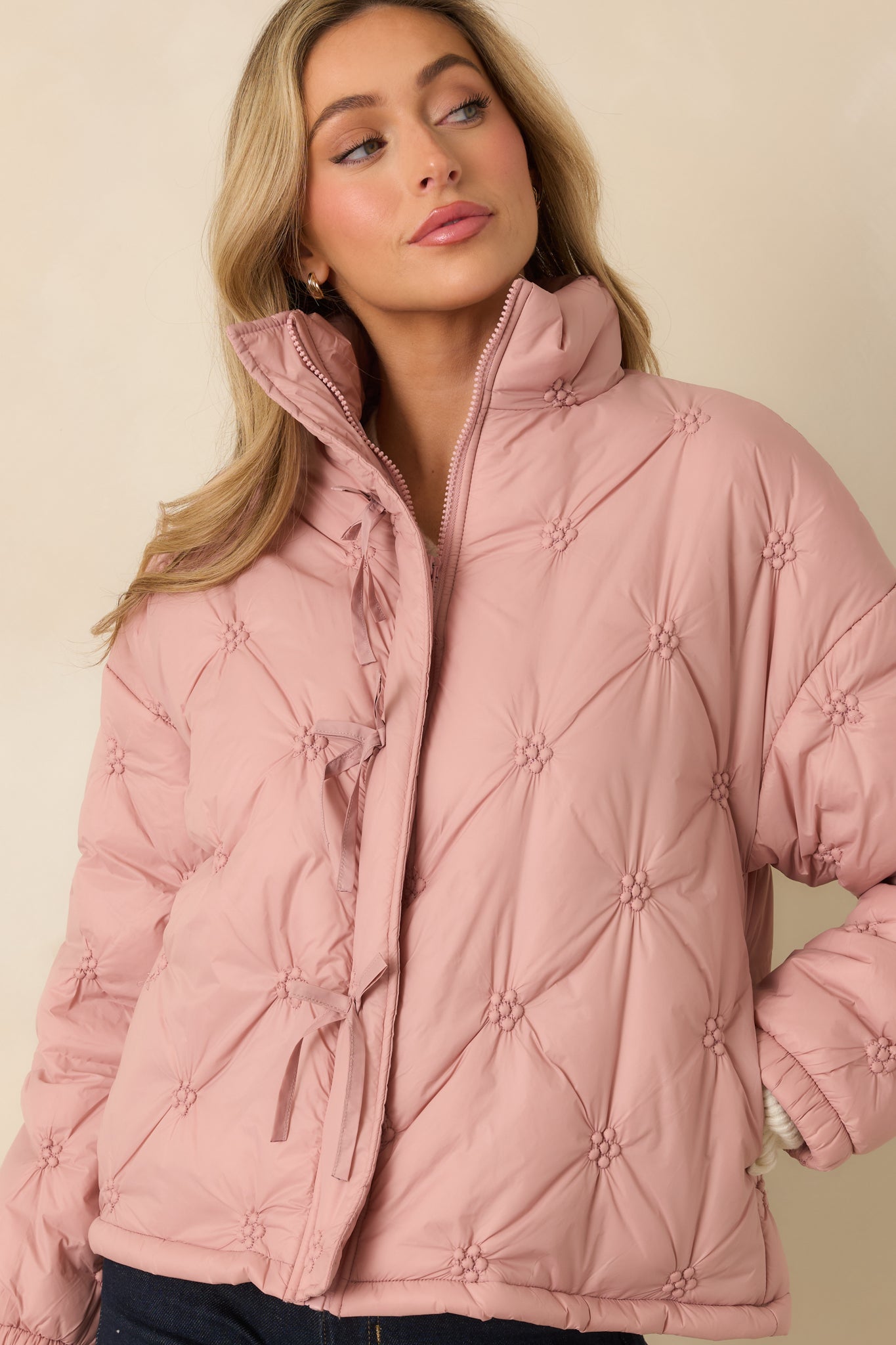 Cropped detail highlighting the stand collar and elasticized cuff of the blush pink quilted puffer jacket.