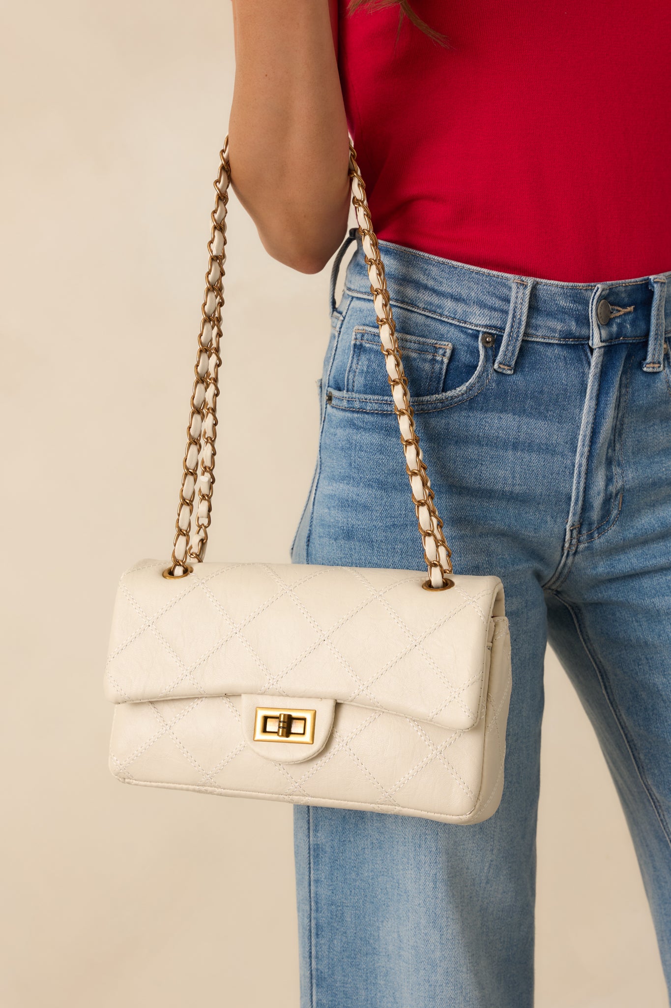Detail crop showcasing the chain strap interwoven with white faux leather and the bag’s textured quilting.