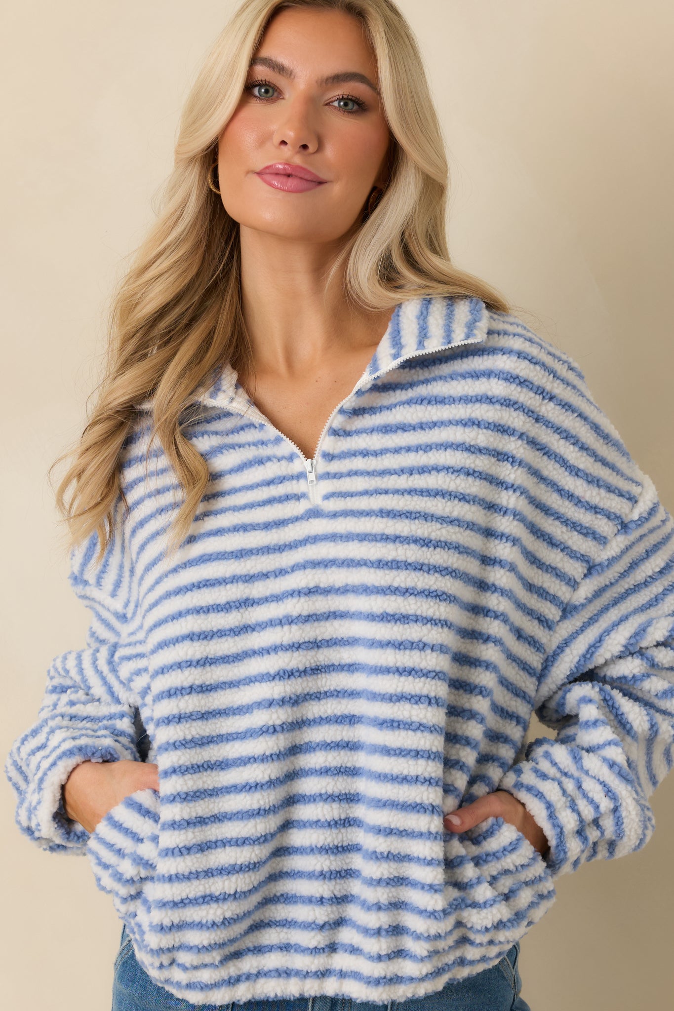 Close front crop showing drop shoulder seam and soft striped knit fabric of blue pullover.