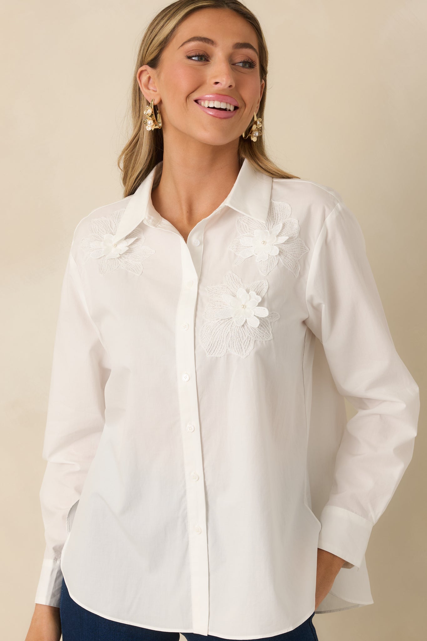 Front-centered crop showing floral embellishments and smooth woven fabric on white blouse.