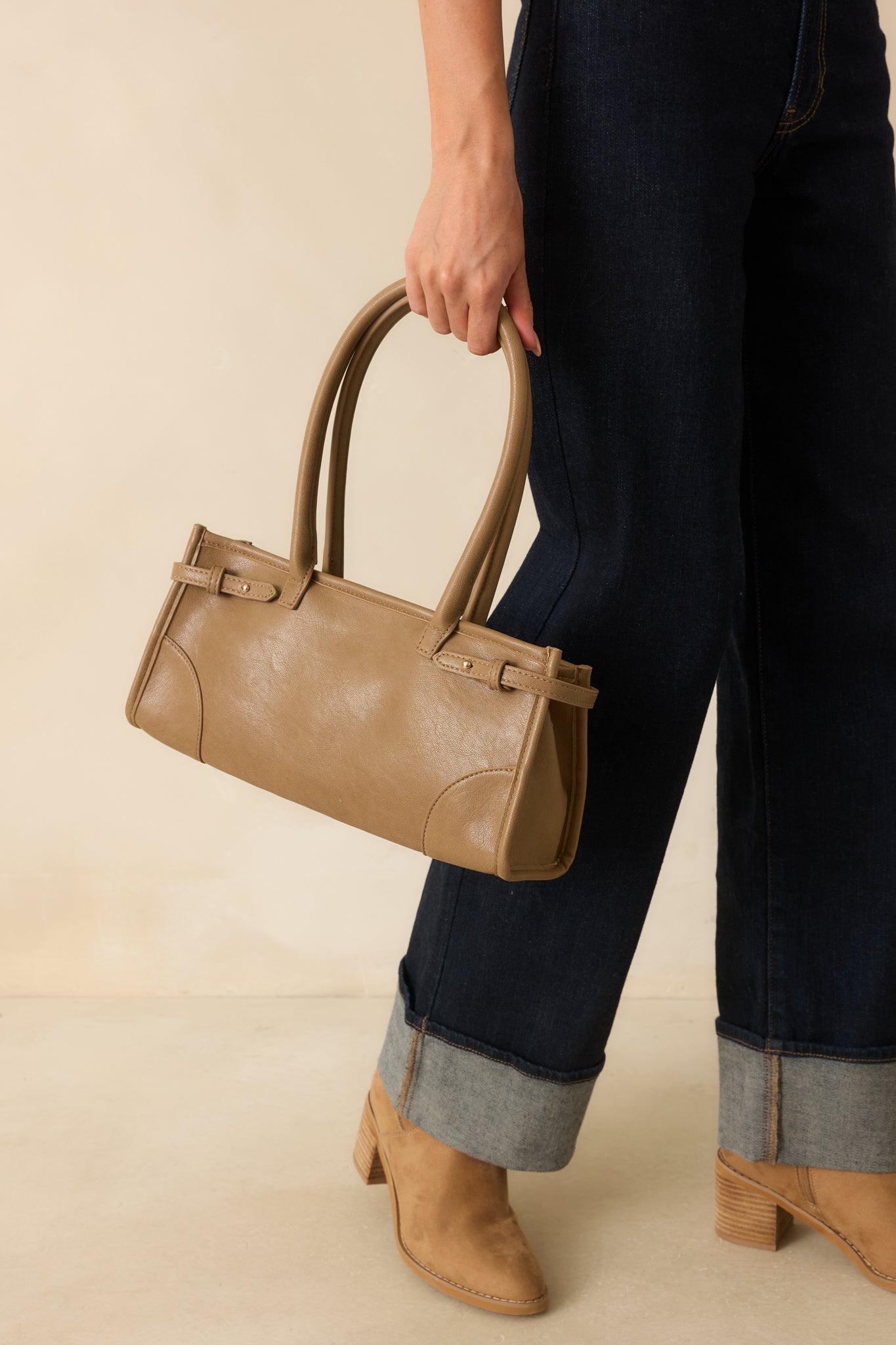 A cropped angle emphasizing the gold hardware, smooth faux leather texture, and rolled handles.