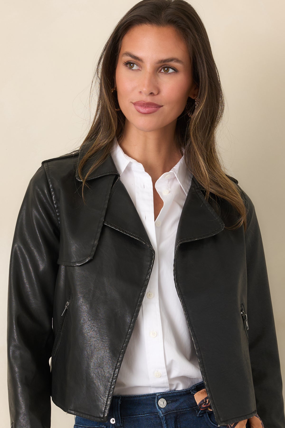 Cropped black faux leather jacket featuring wide lapels and long sleeves with zippered cuffs.