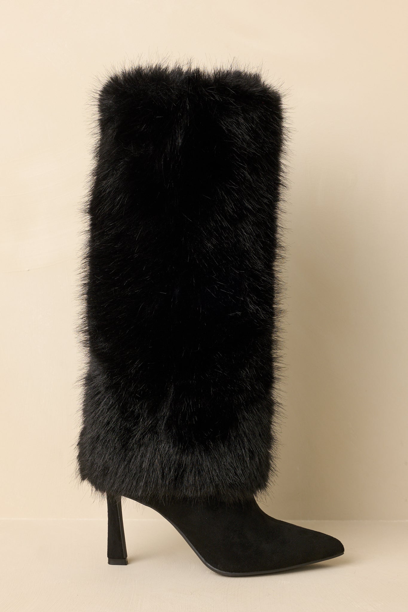 Cropped view of black pointed-toe stiletto boots highlighting the faux suede footbed and plush faux fur shaft.