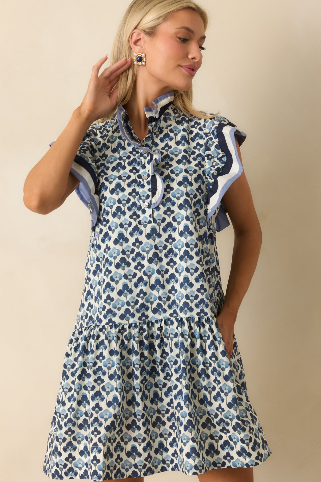 Cropped shot highlighting the flutter sleeves and contrast stripe trim on the blue floral dress.