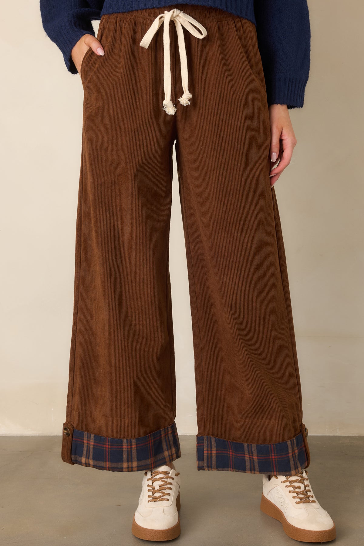 The cropped brown silhouette is finished with bold navy plaid cuffs for a distinctive contrast.