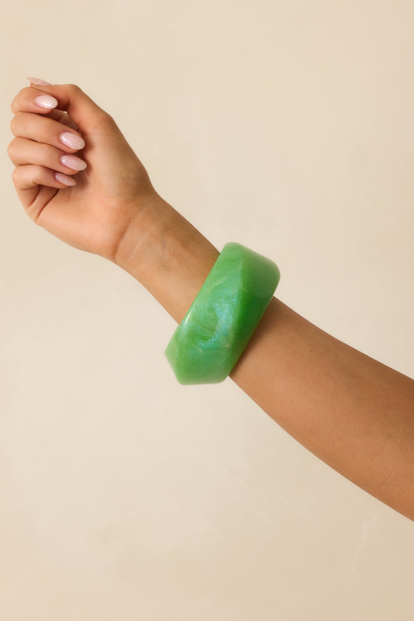 A cropped shot highlighting the chunky silhouette and subtle glitter details of the bracelet.